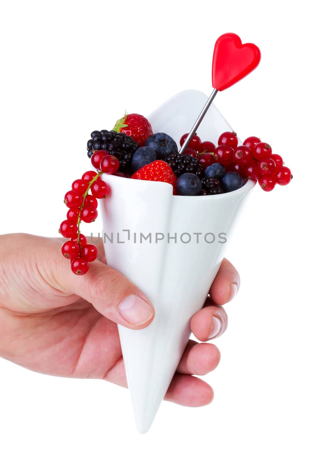 Hand holding French fries bag filled with fresh fruit like healthy snack over white background