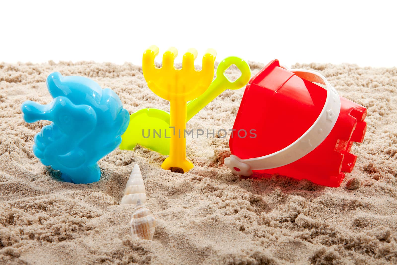 colorful plastic toys on the beach over white background