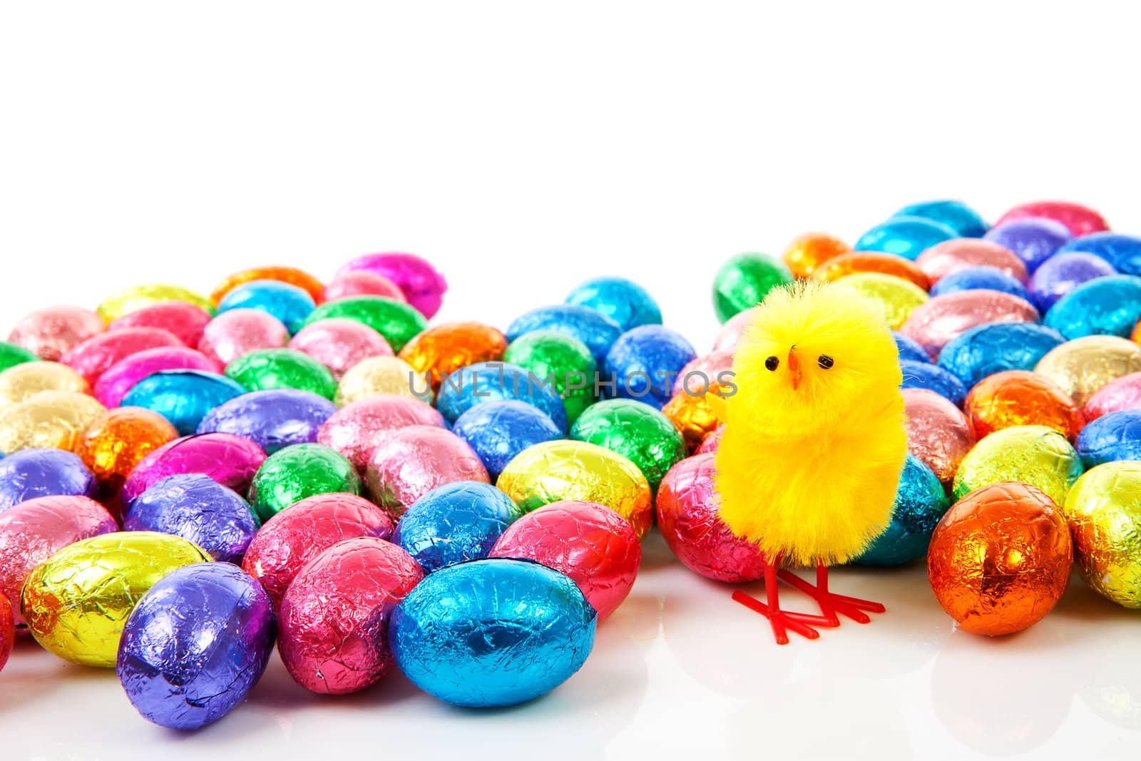 Colorful chocolate easter eggs and yellow chicken over white background