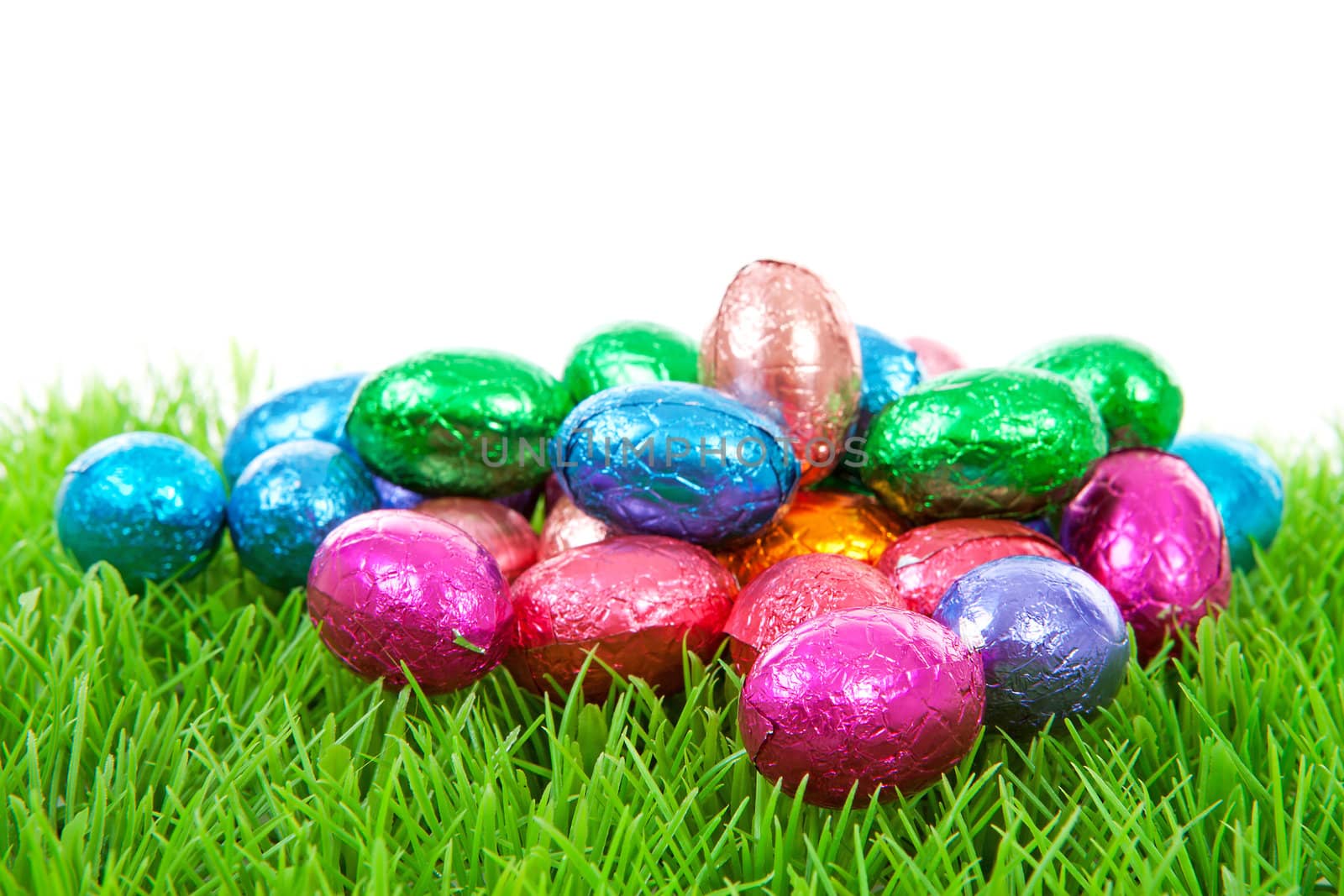 colorful chocolate easter eggs on grass over white background