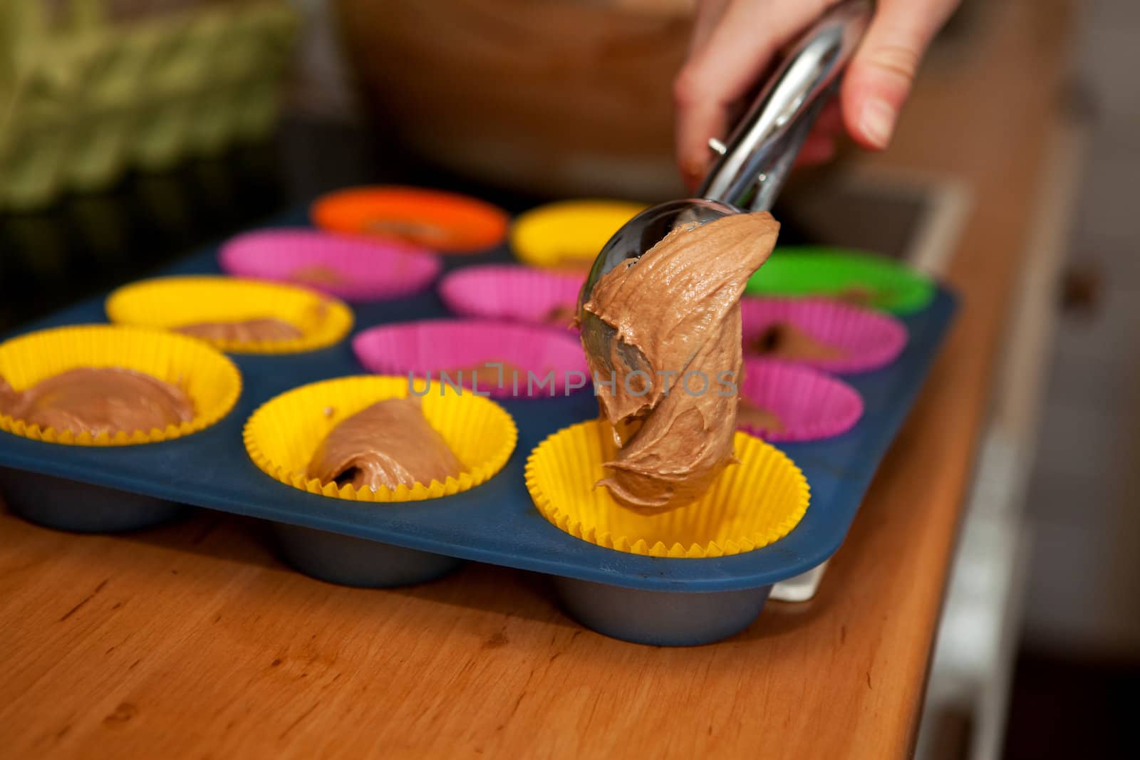 Hand is making colorful cupcakes in kitchen