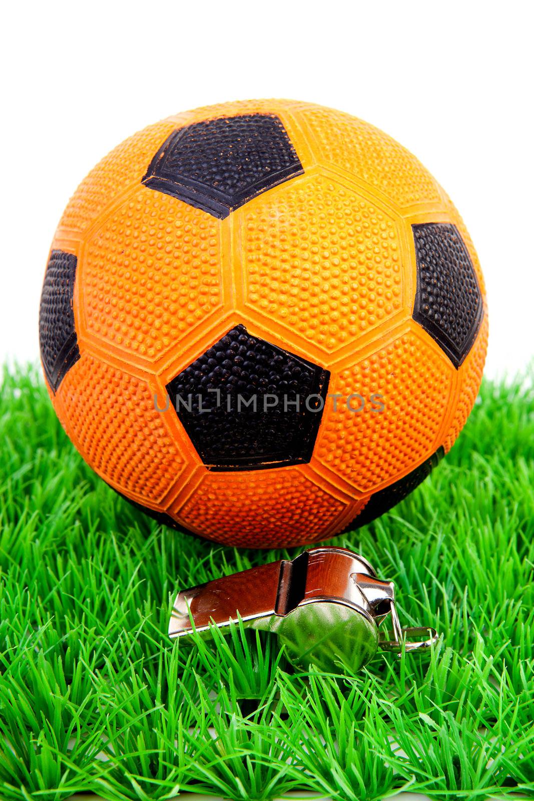 Orange soccer ball and flute on grass over white background