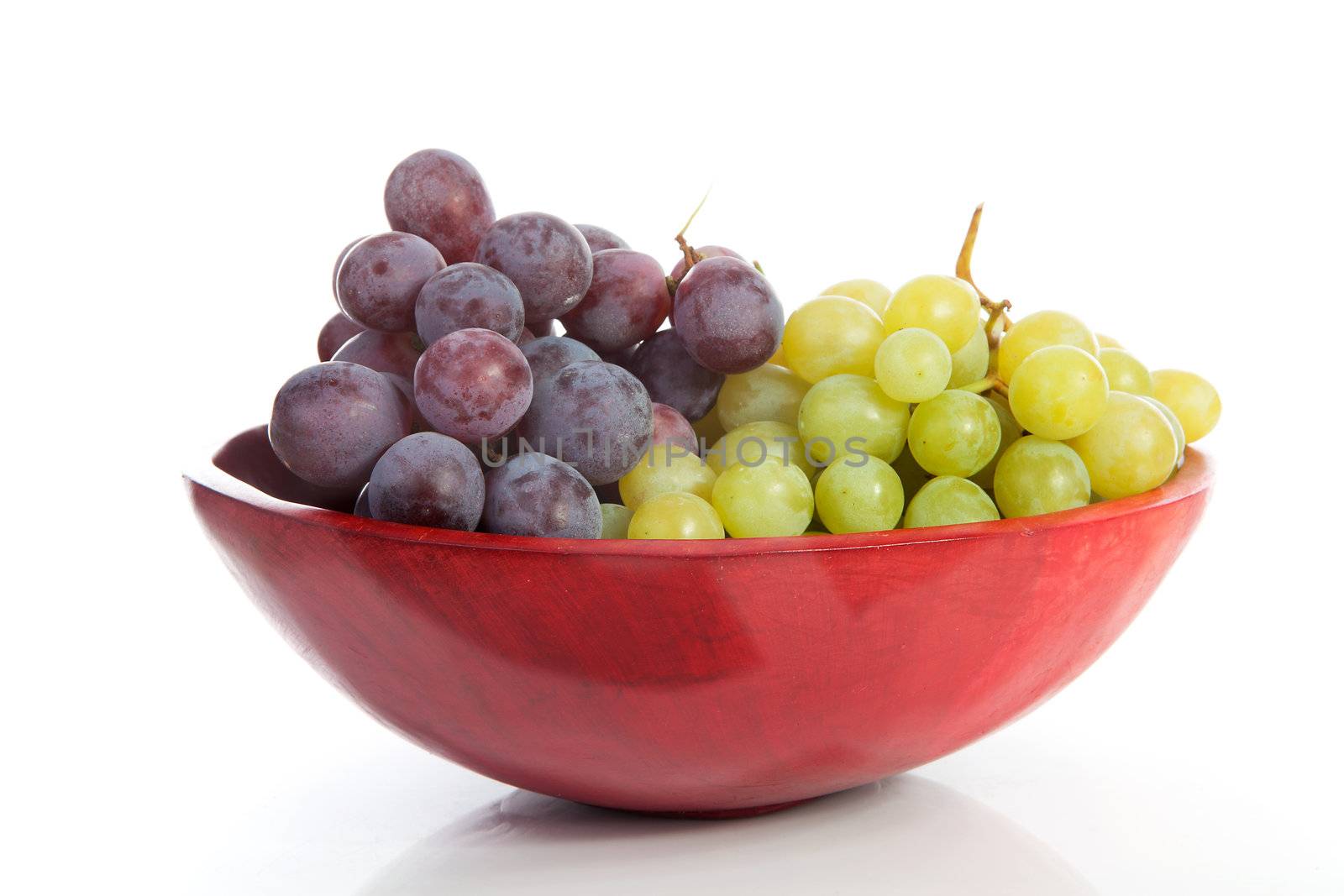 Red bowl with grapes over white background