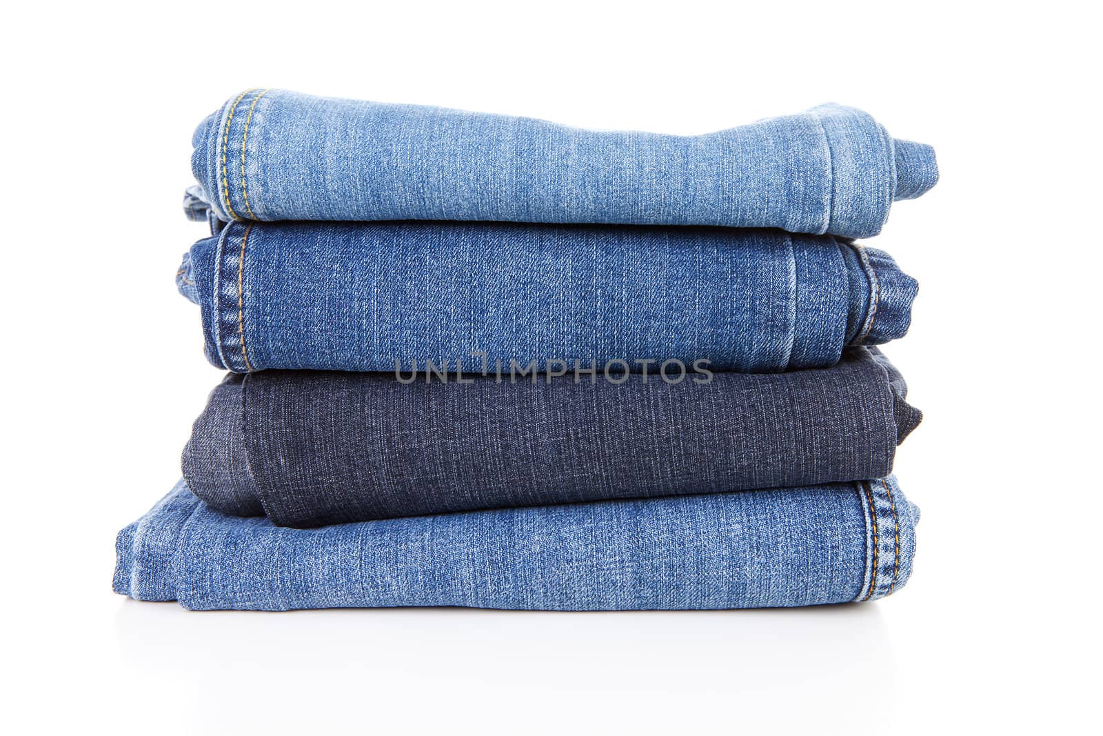 Pile of blue jeans over white background