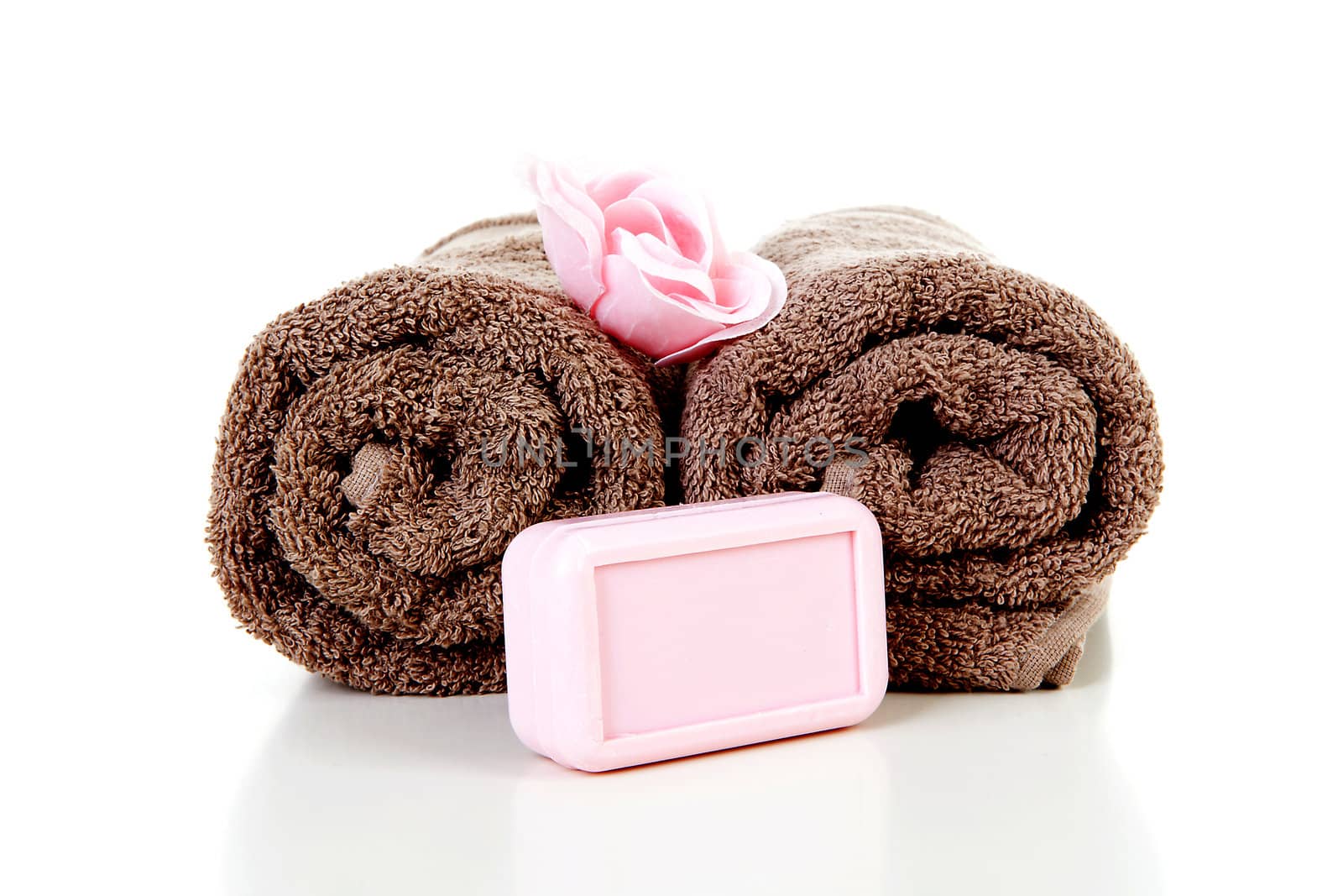 Two brown rolled towels and soap over white background
