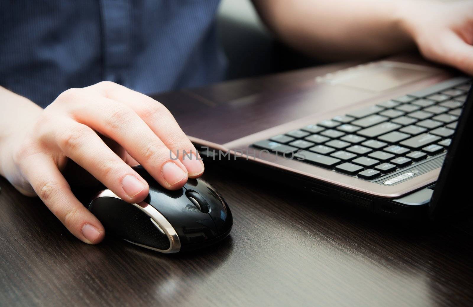 Human hand on computer mouse. Laptop on desk. by simpson33