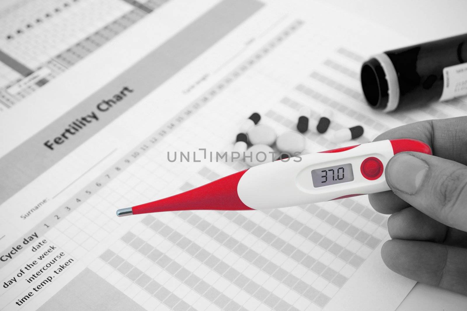 Red thermometer on black and white fertility composition