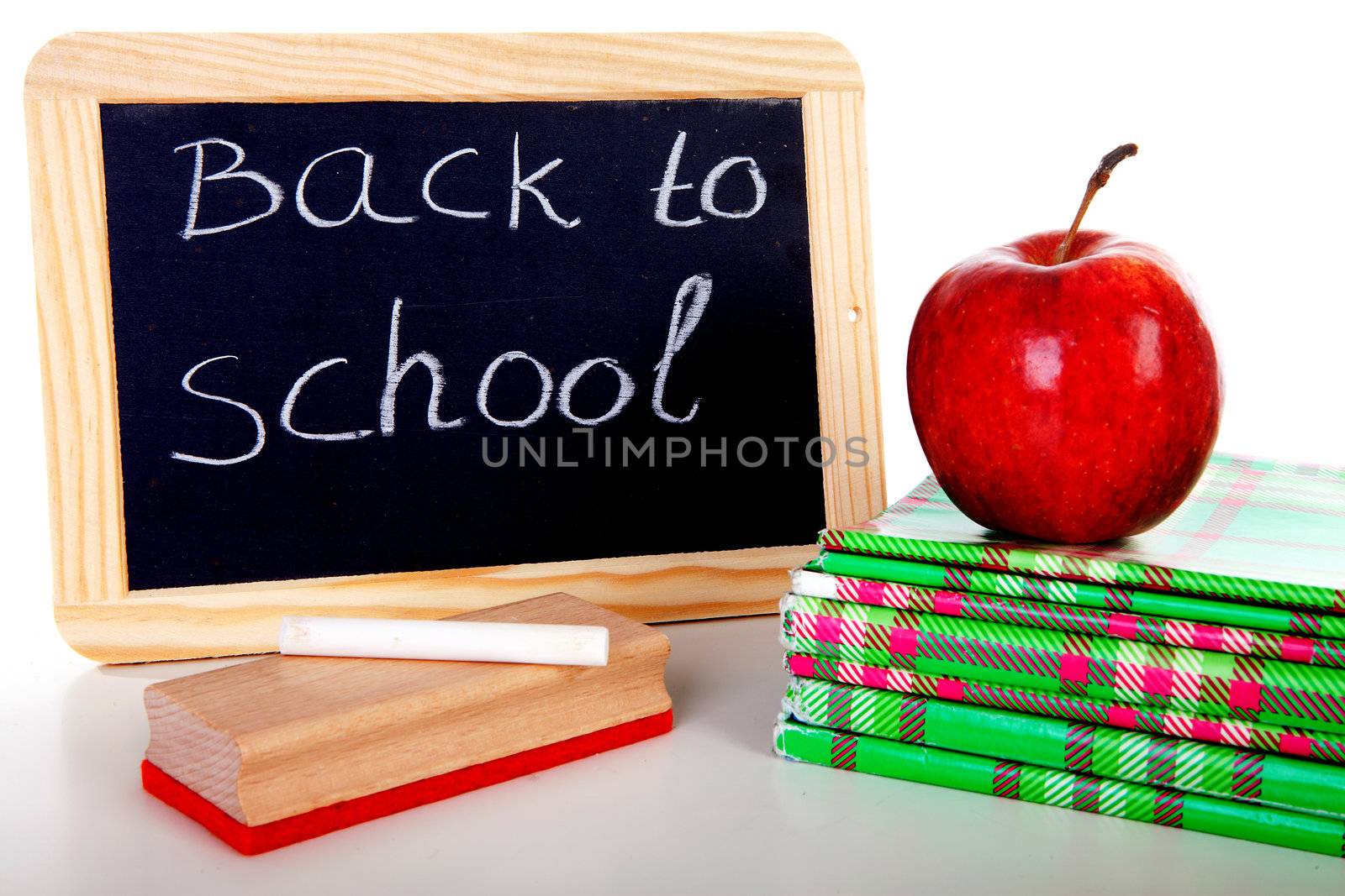 back to school: blackboard slate and stack of books with apple on top over white background 
