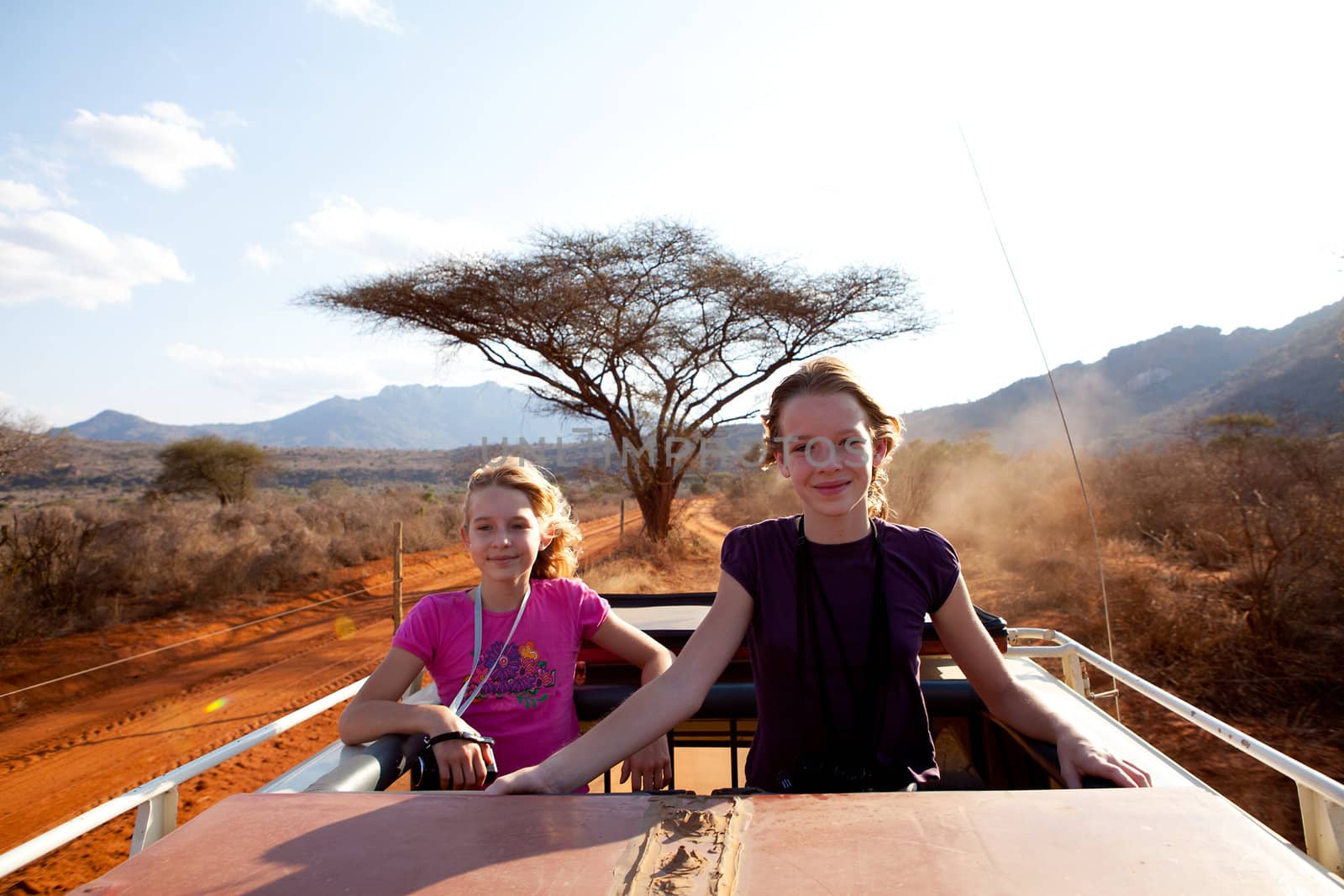 Going on safari: two girls standing on top of jeep
