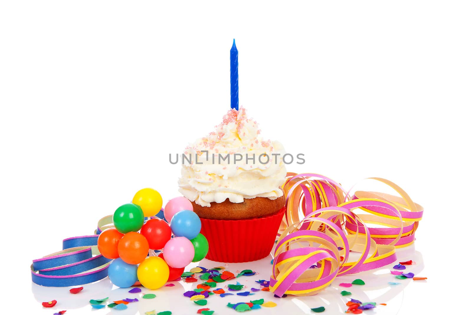 Birthday cupcake with whipped cream, party streamers and colorful confetti over white background