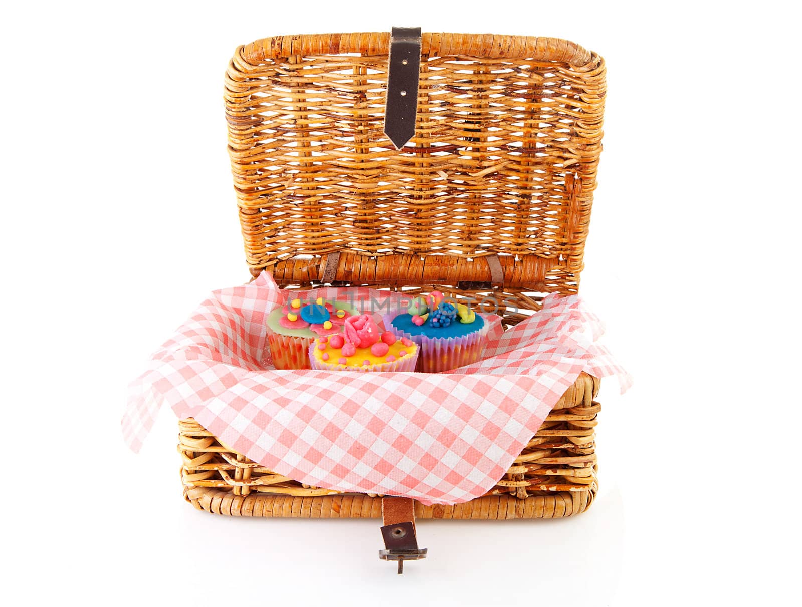Picnic basket with decorated cupcakes over white background