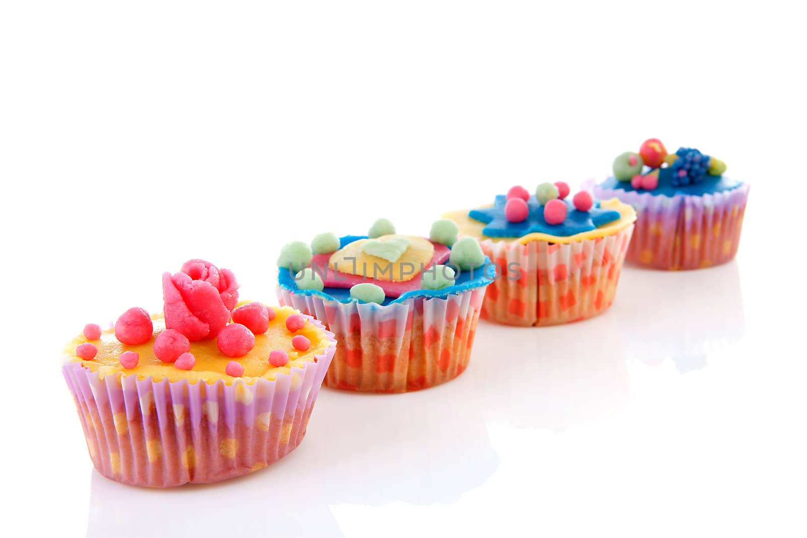 Row cupcakes with colorful marzipan decoration over white background