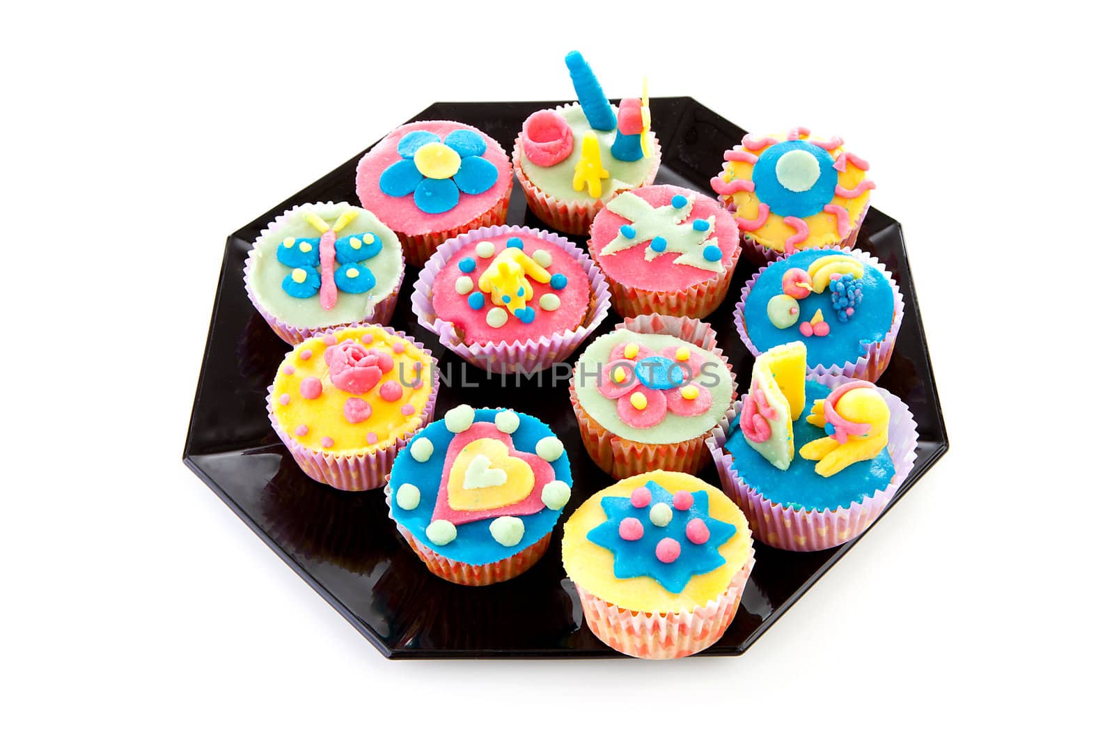 Black plate with decorated cupcakes over white background