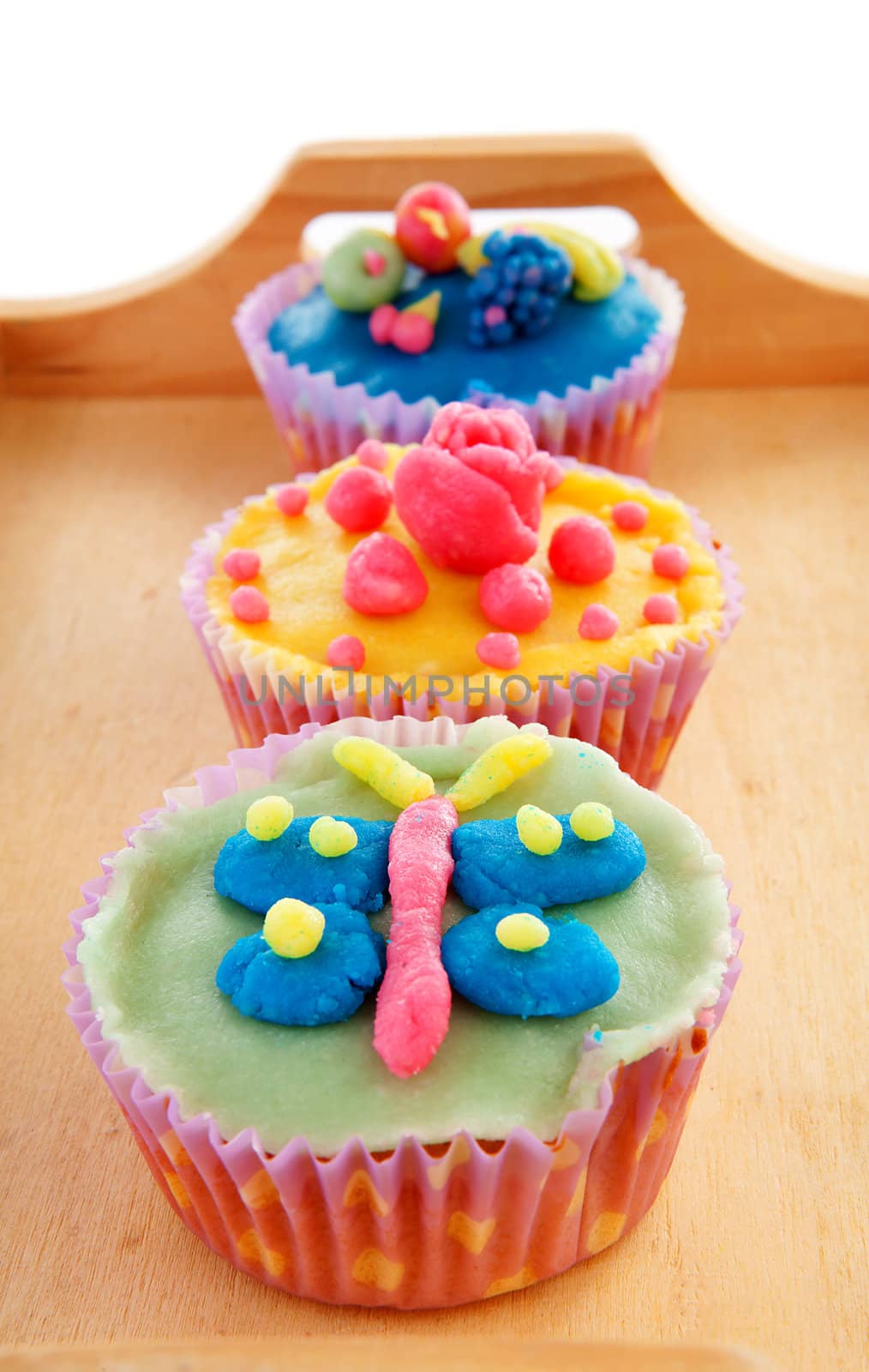 Tray with three delicious decorated colorful cupcakes