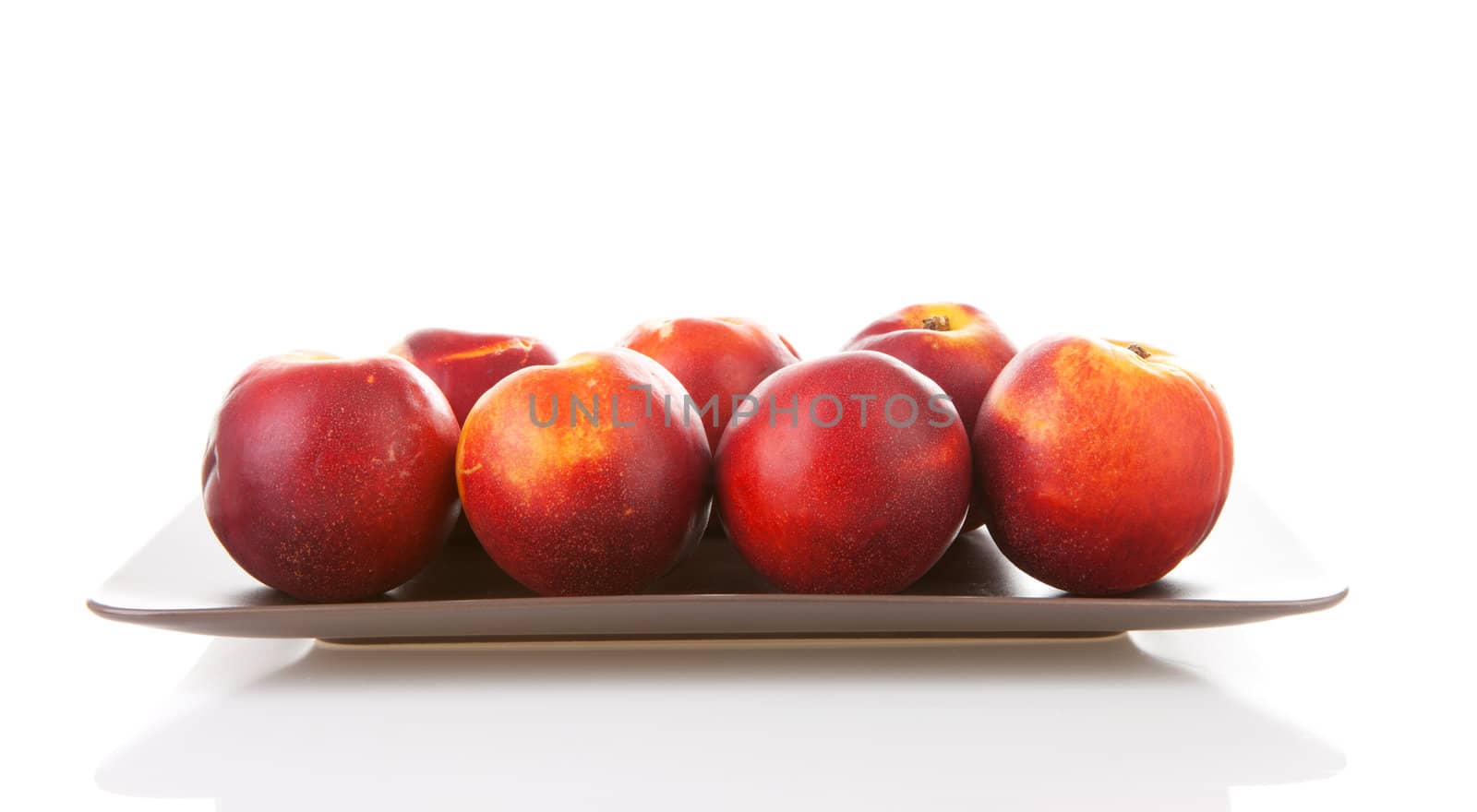 Plate with fresh nectarines over white background