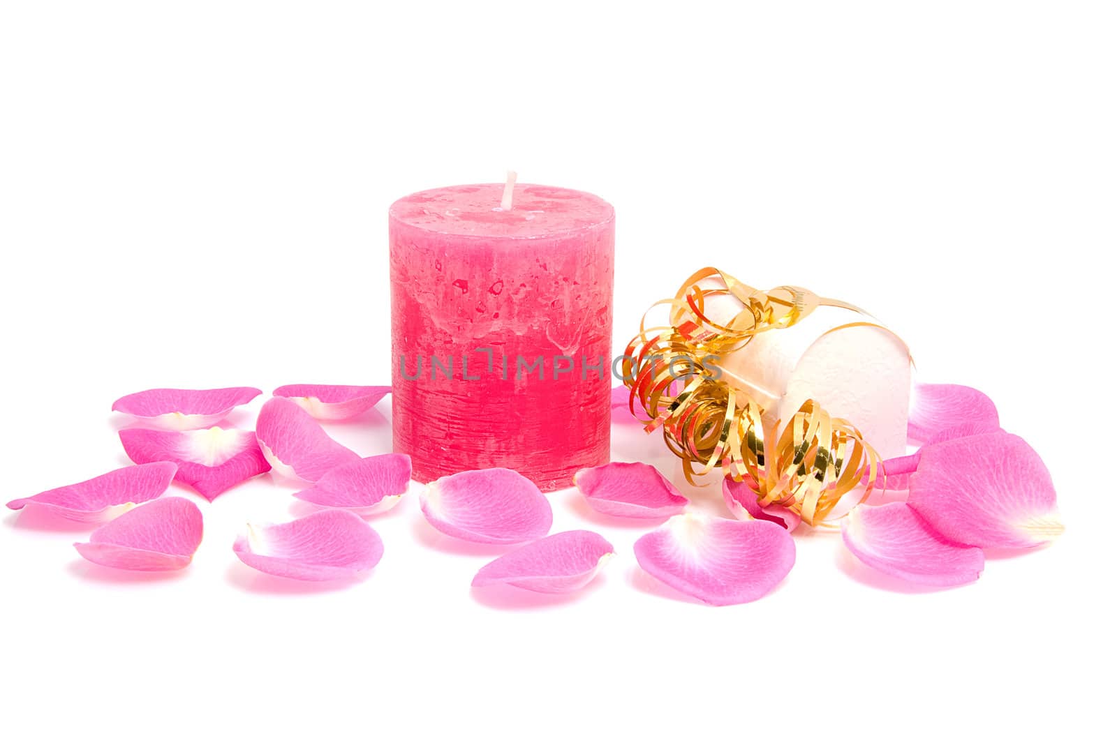 Pink candle with rose leaves and box of chocolate for Valentine's day over white background