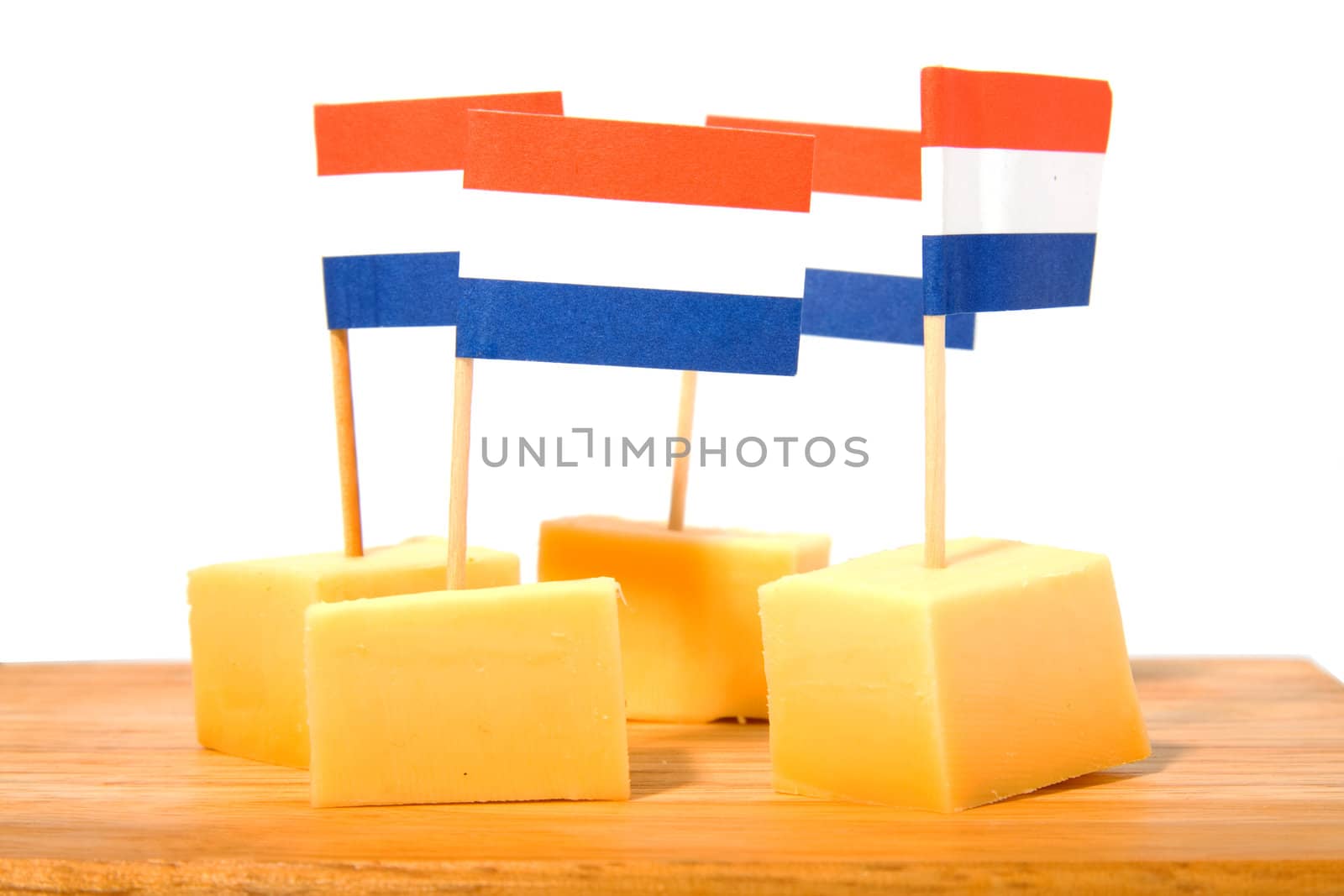 cheese cubes on wooden board with Dutch flags for party over white background