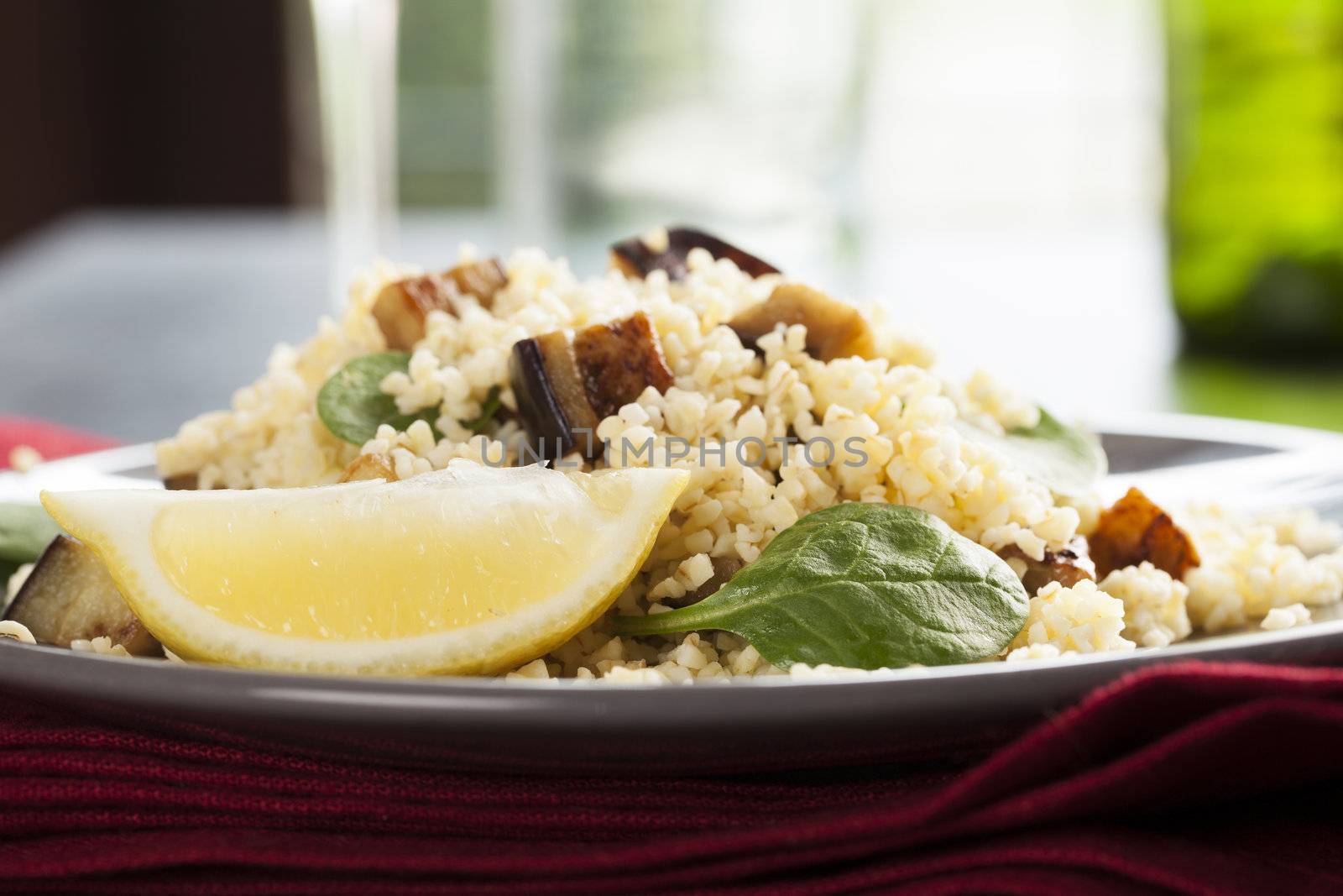 Bulgur salad with spinach roasted eggplant and a lemon wedge