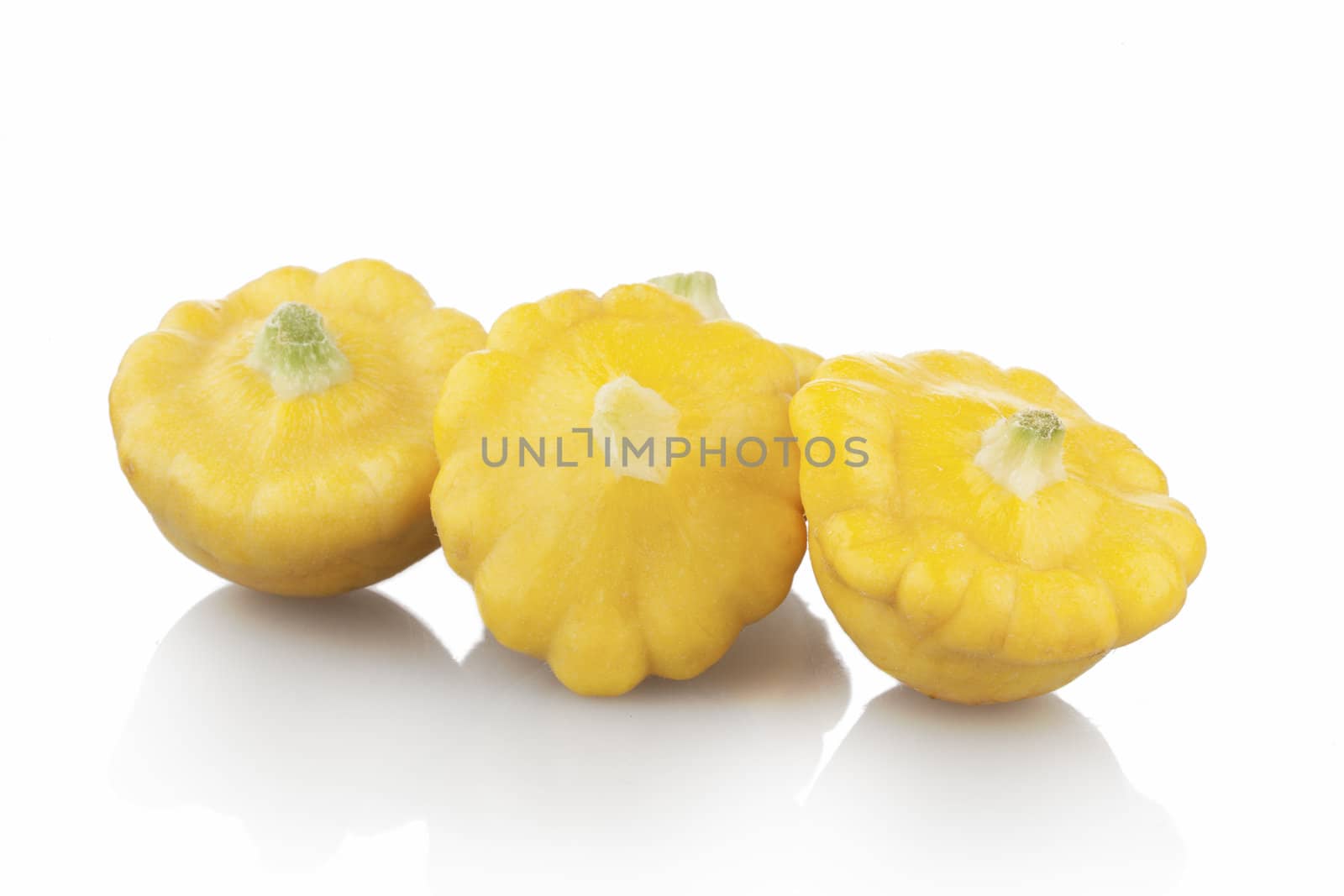 Three pattypan squash on white background with shadows