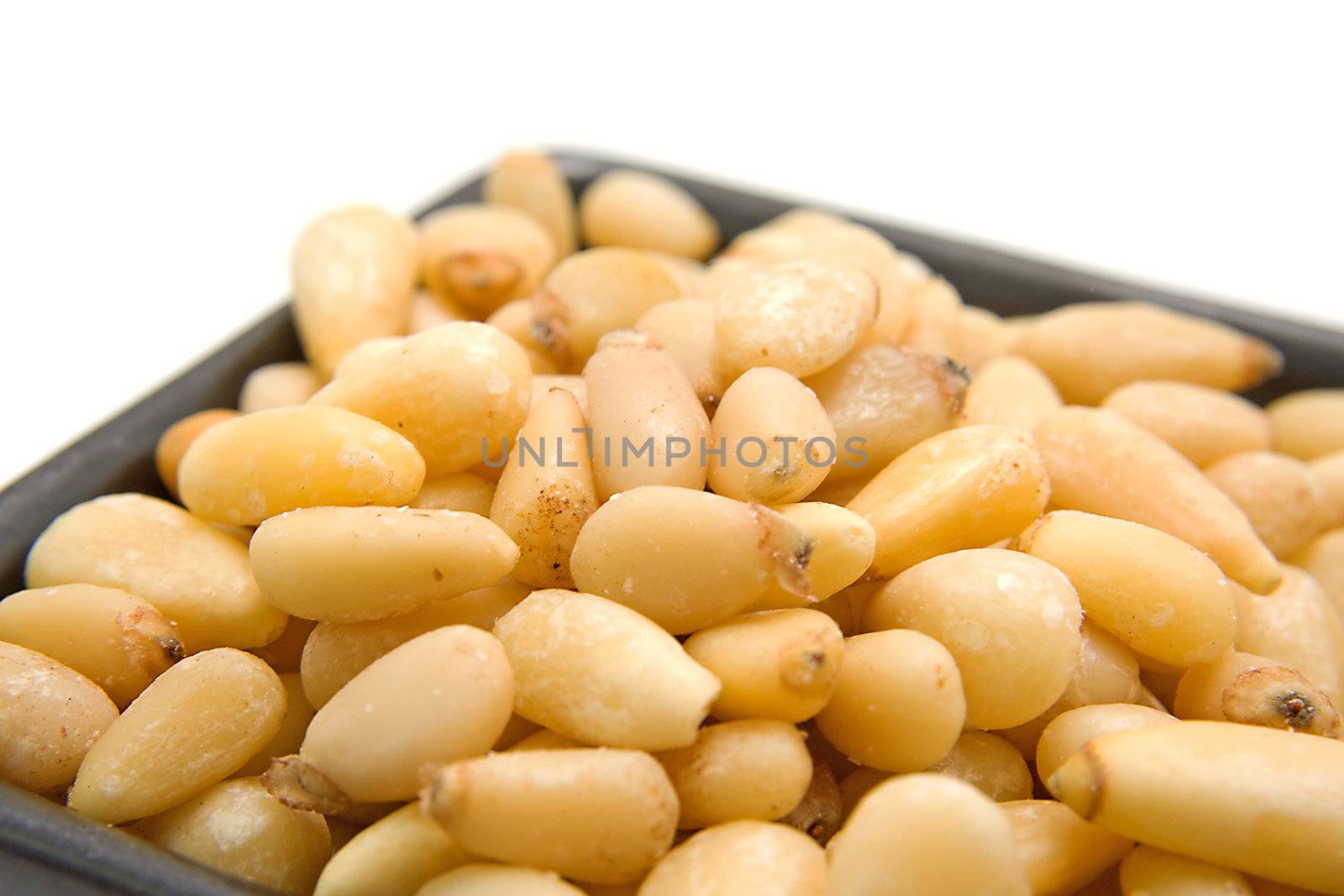 little bowl with pine nuts in closeup over white background