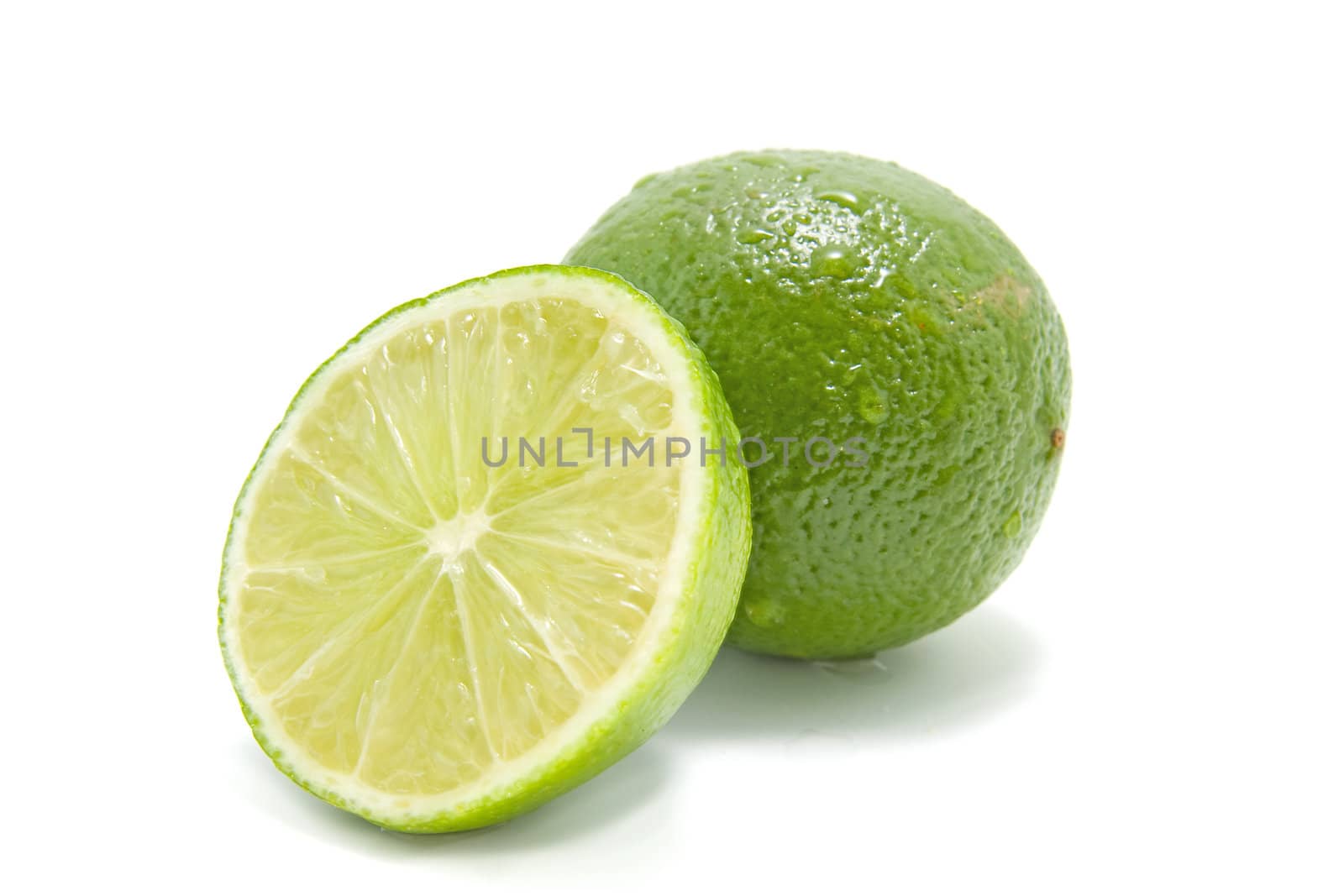 fresh juicy green lime, one whole and one half, with waterdrops. Isolated on white background