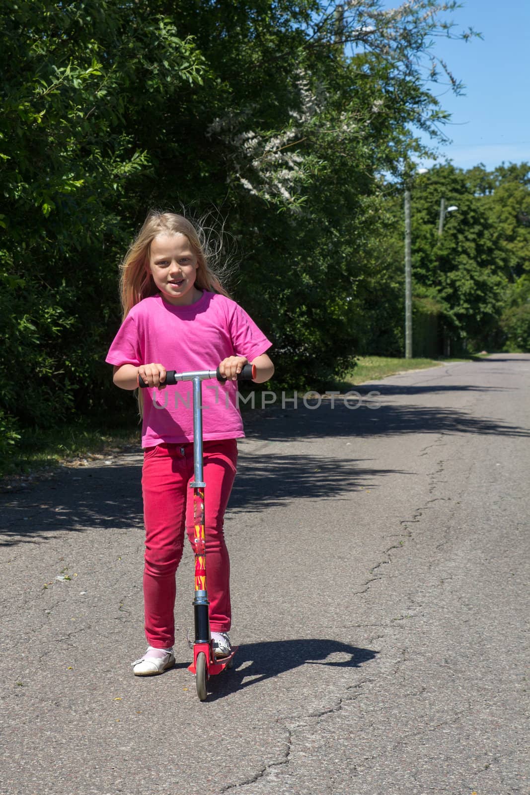 little girl rides a scooter on a rural road