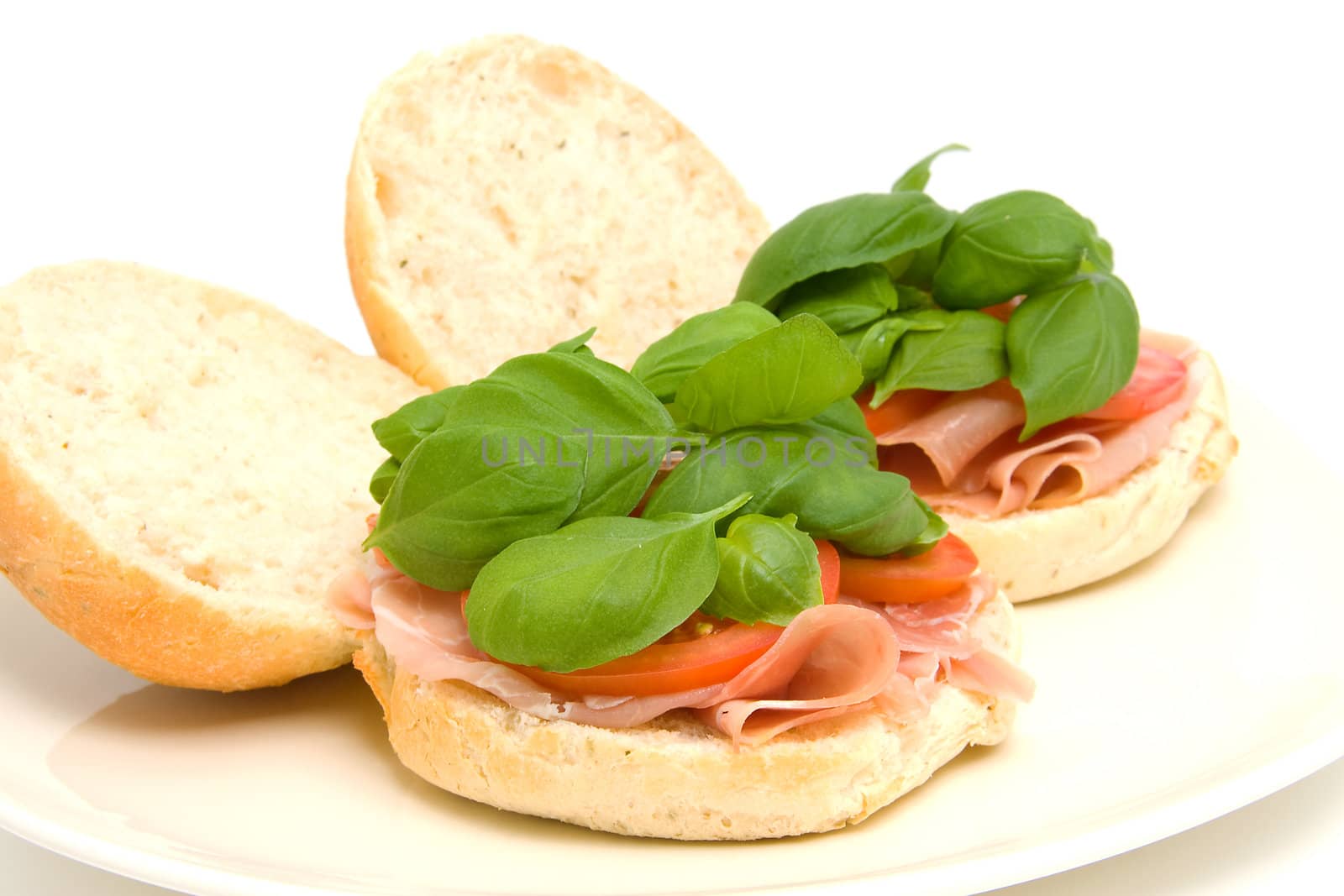 Fresh healthy sandwich with basil and tomatoes on plate over white background