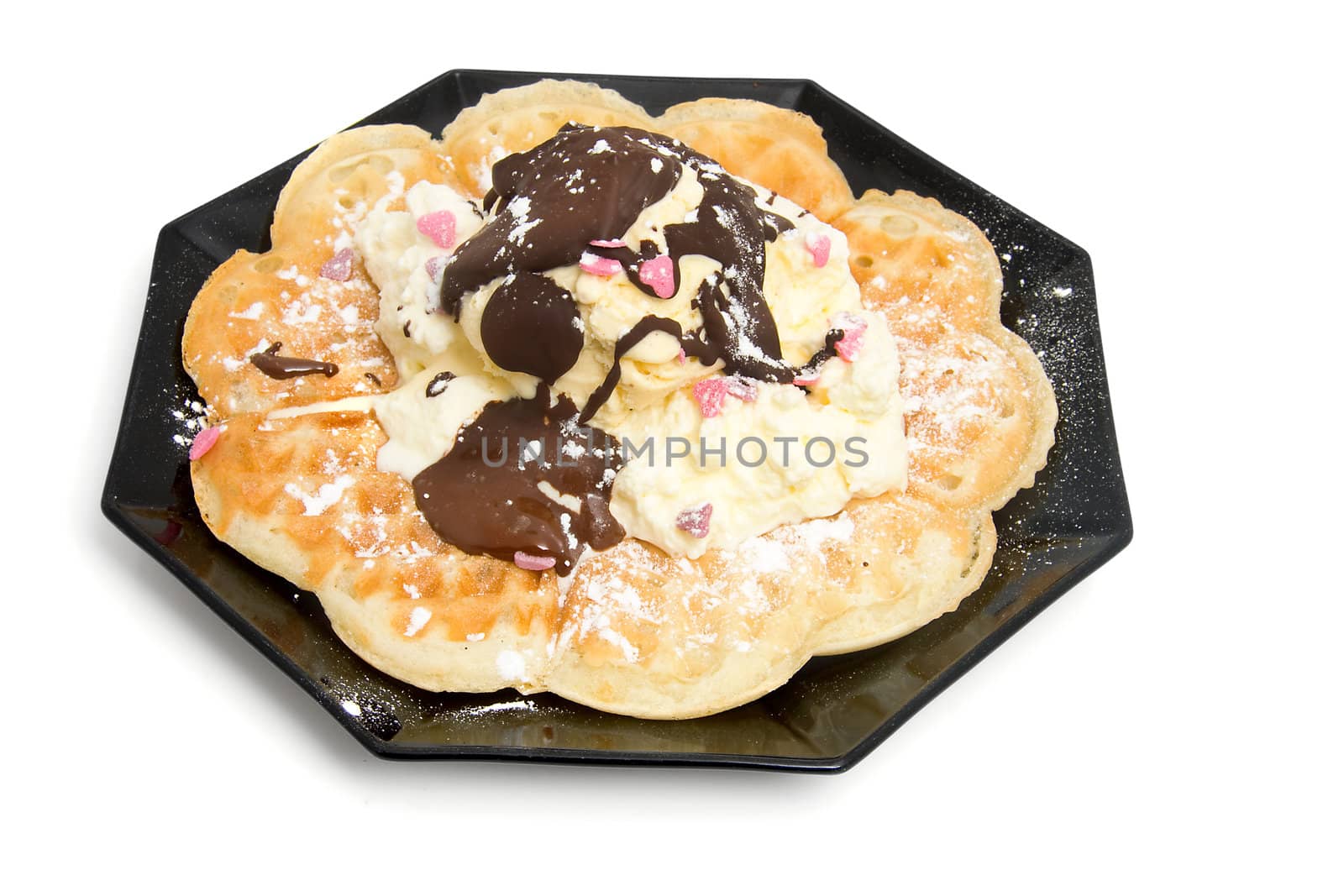 delicious dessert with waffle and ice cream on black plate over white background