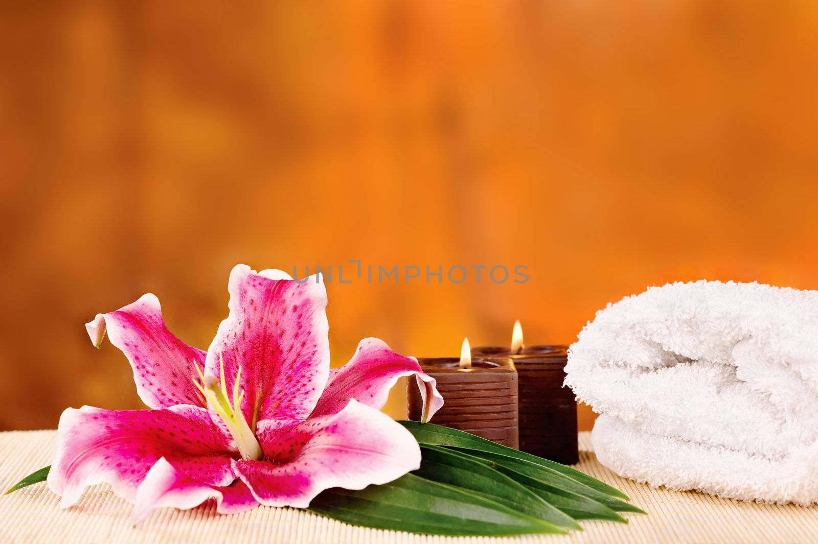 Romantic candle set with orchid in front and white towel 