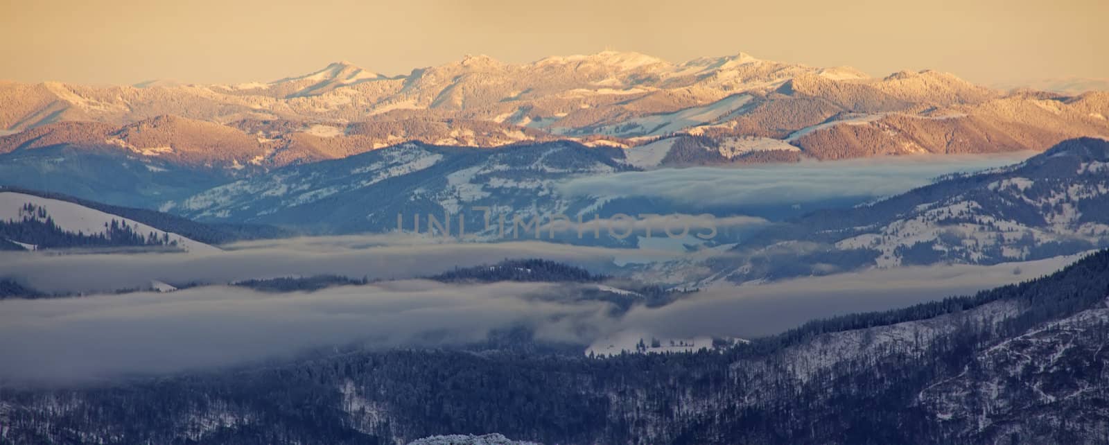 Snow mountain at sunrise, fog in the valley