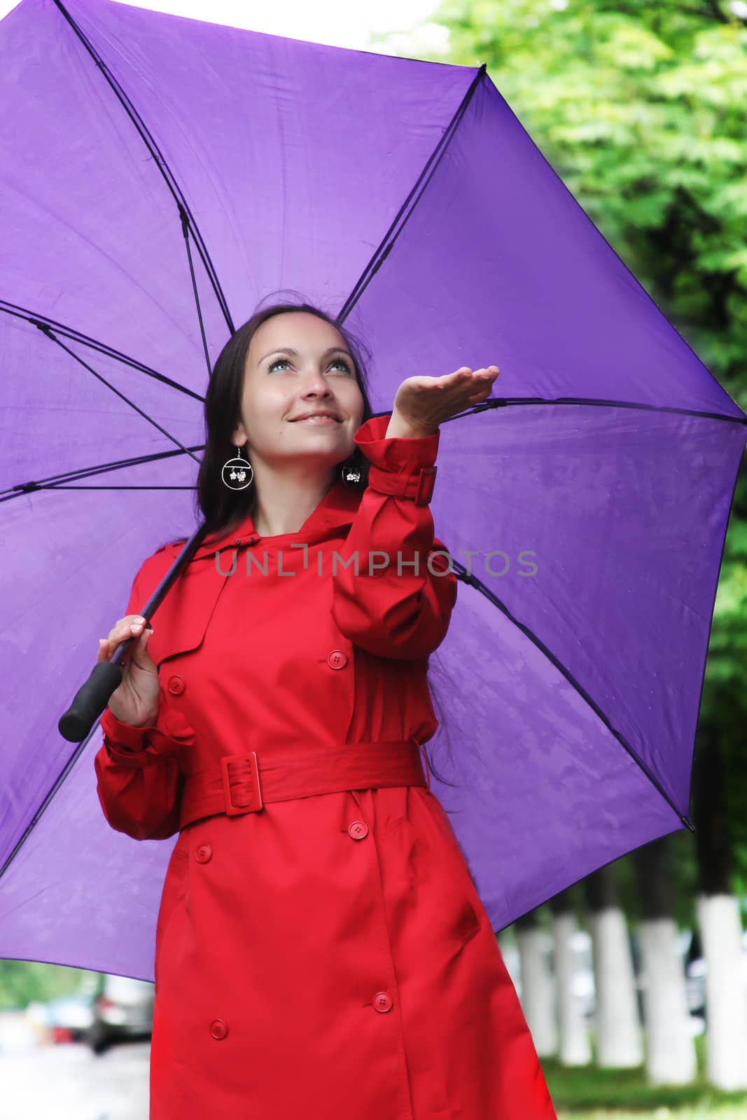 Happy woman with umbrella catching rain drops