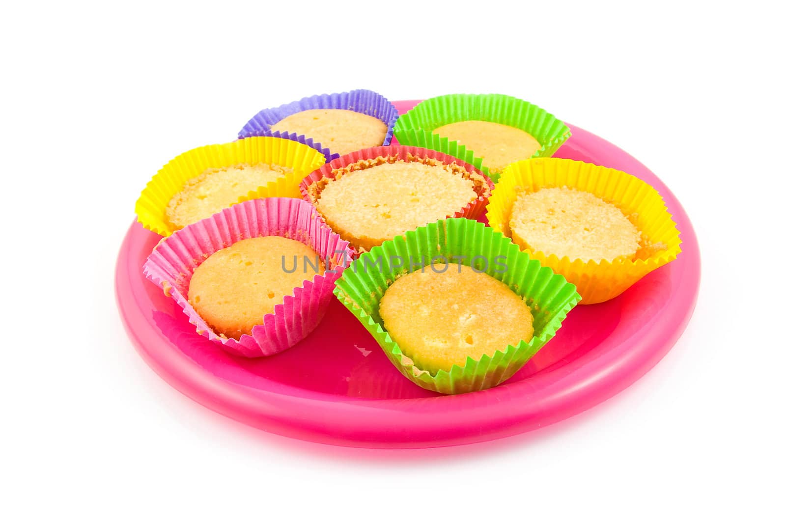Home made cupcakes in colorful cups on pink plate, isolated on white background