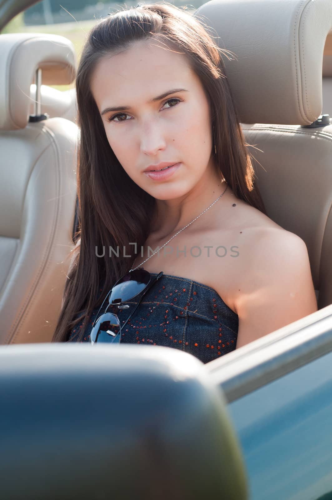 Outdoor shot of beautiful brunette woman with long  in car