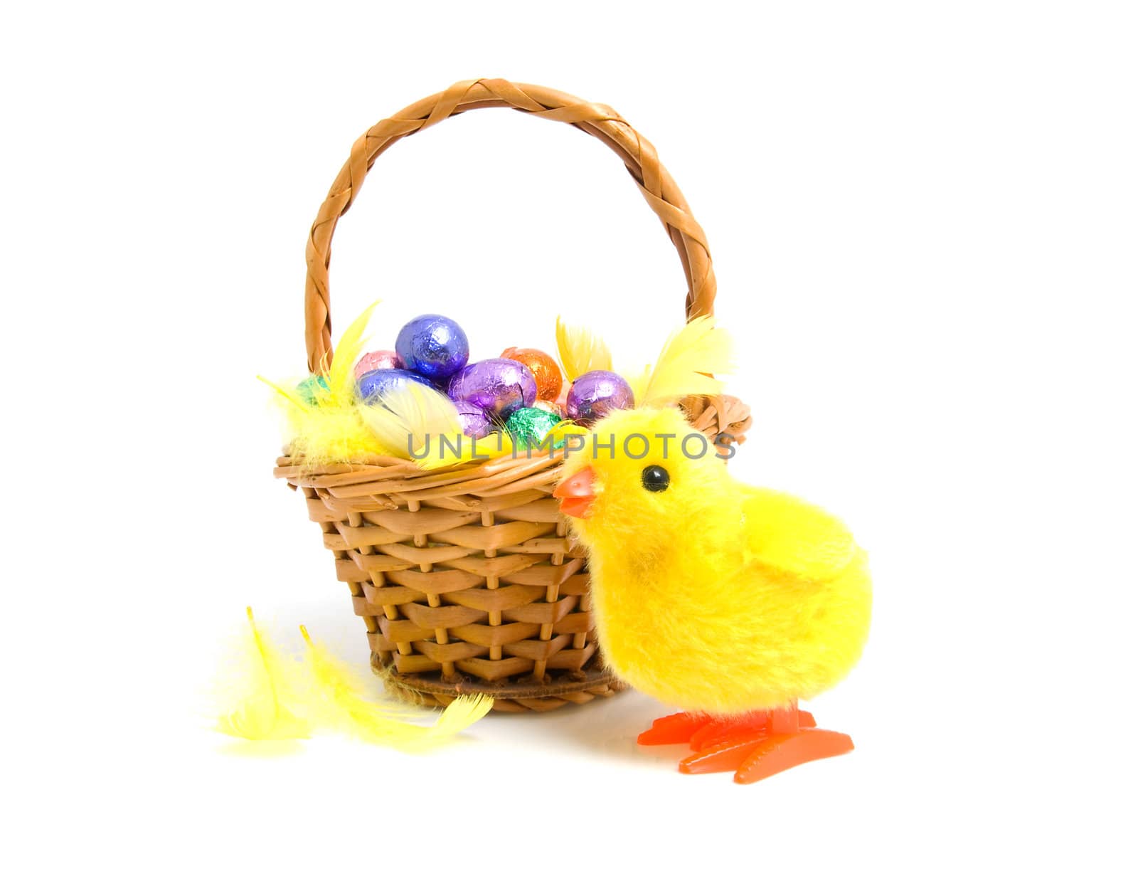Cane basket with chocolate easter eggs and yellow chicken over white background