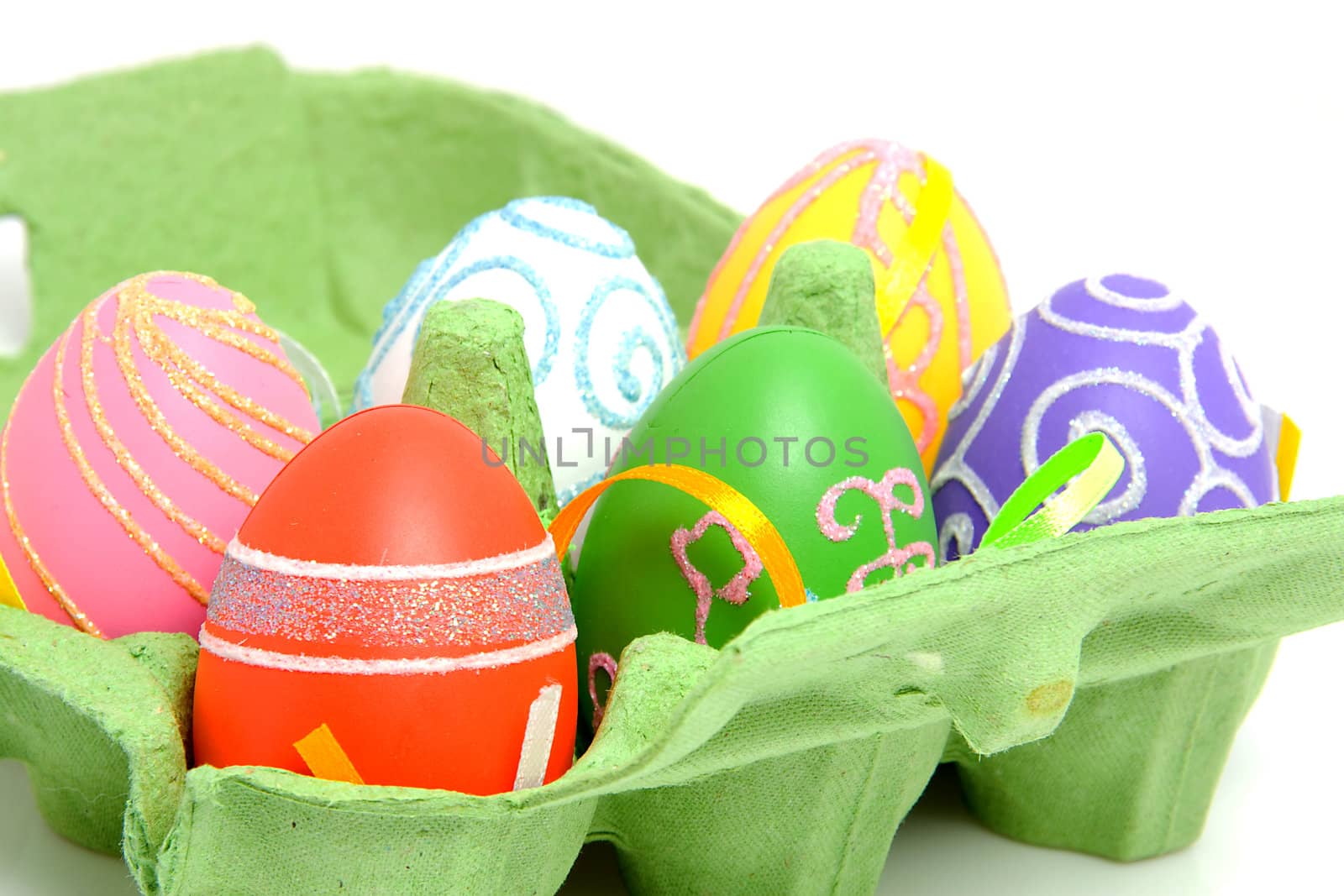 Colorful easter eggs in green carton box over white background