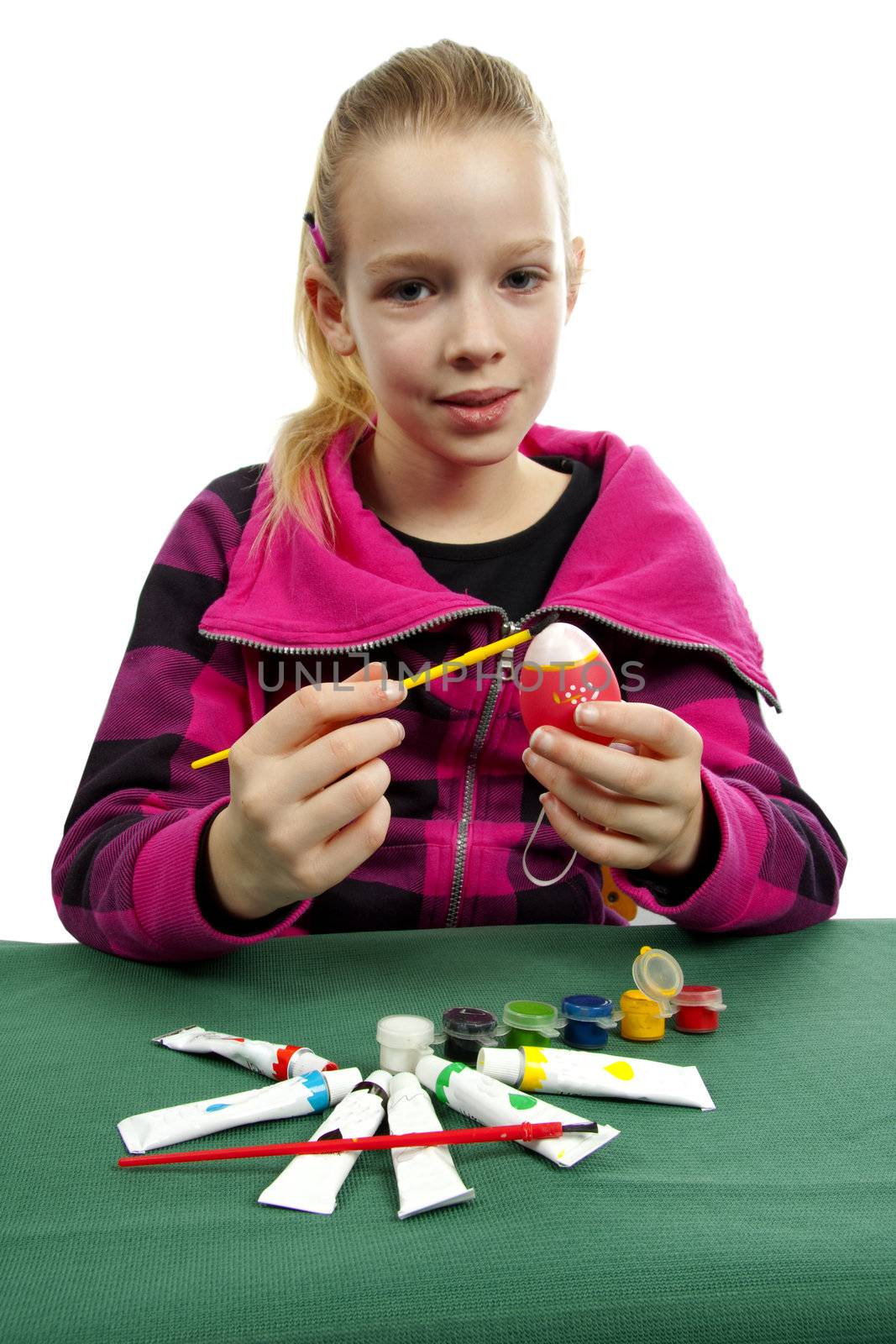 Girl is painting easter egg over white background