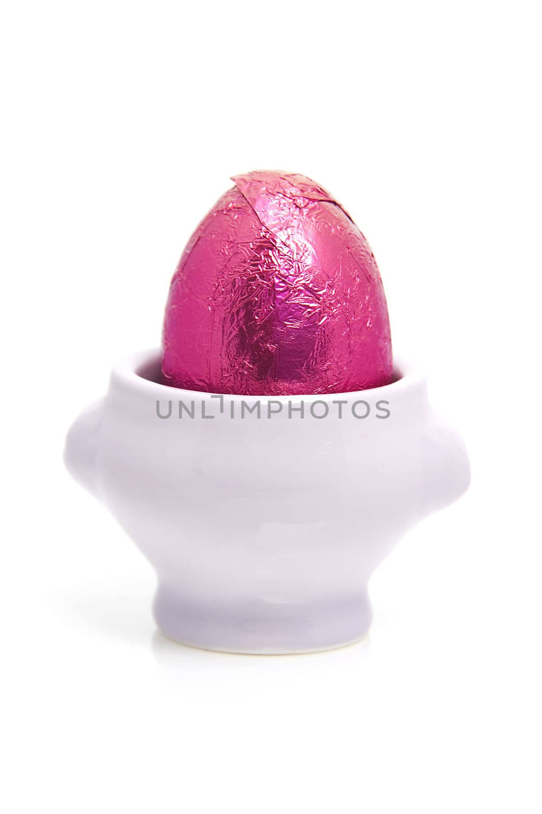 Pink easter egg in cup over white background
