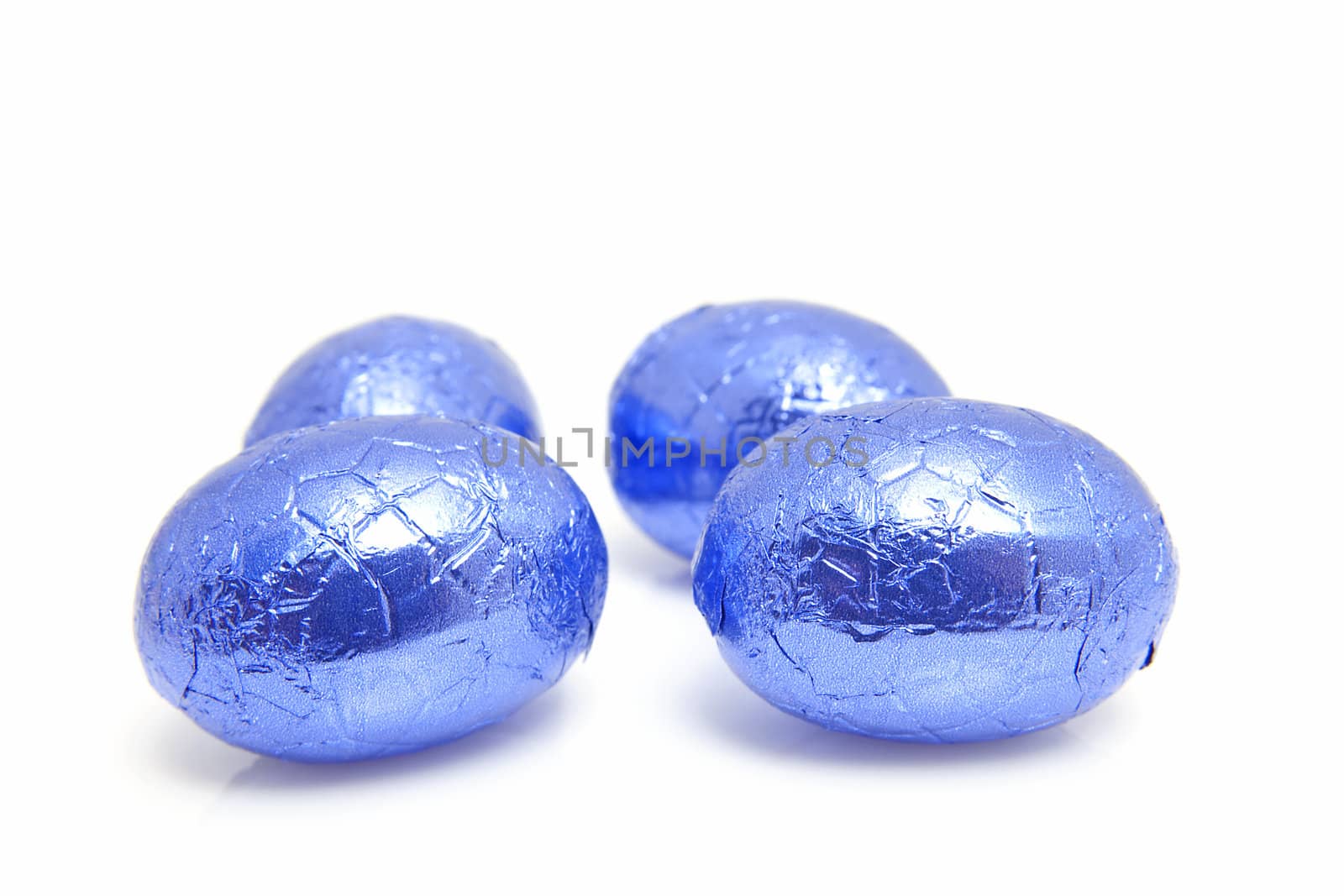 Blue chocolate easter eggs in closeup over white background