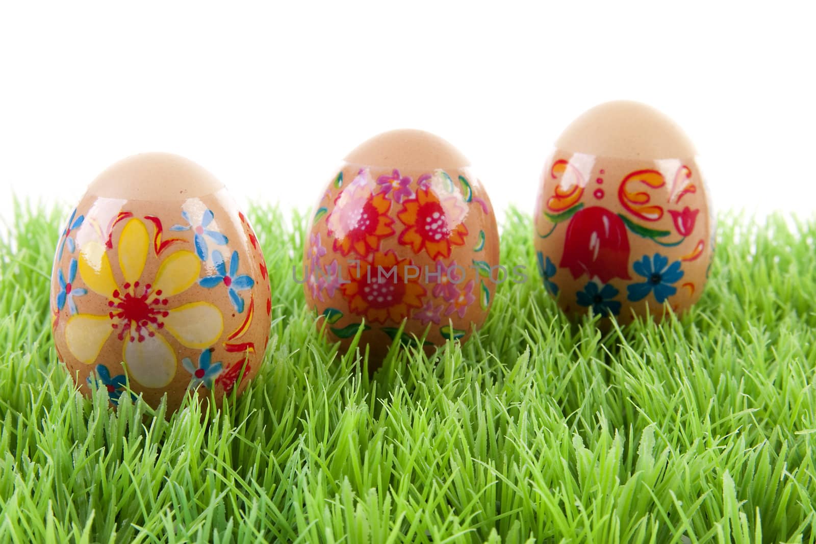 decorated chickens eggs made by children in grass over white background