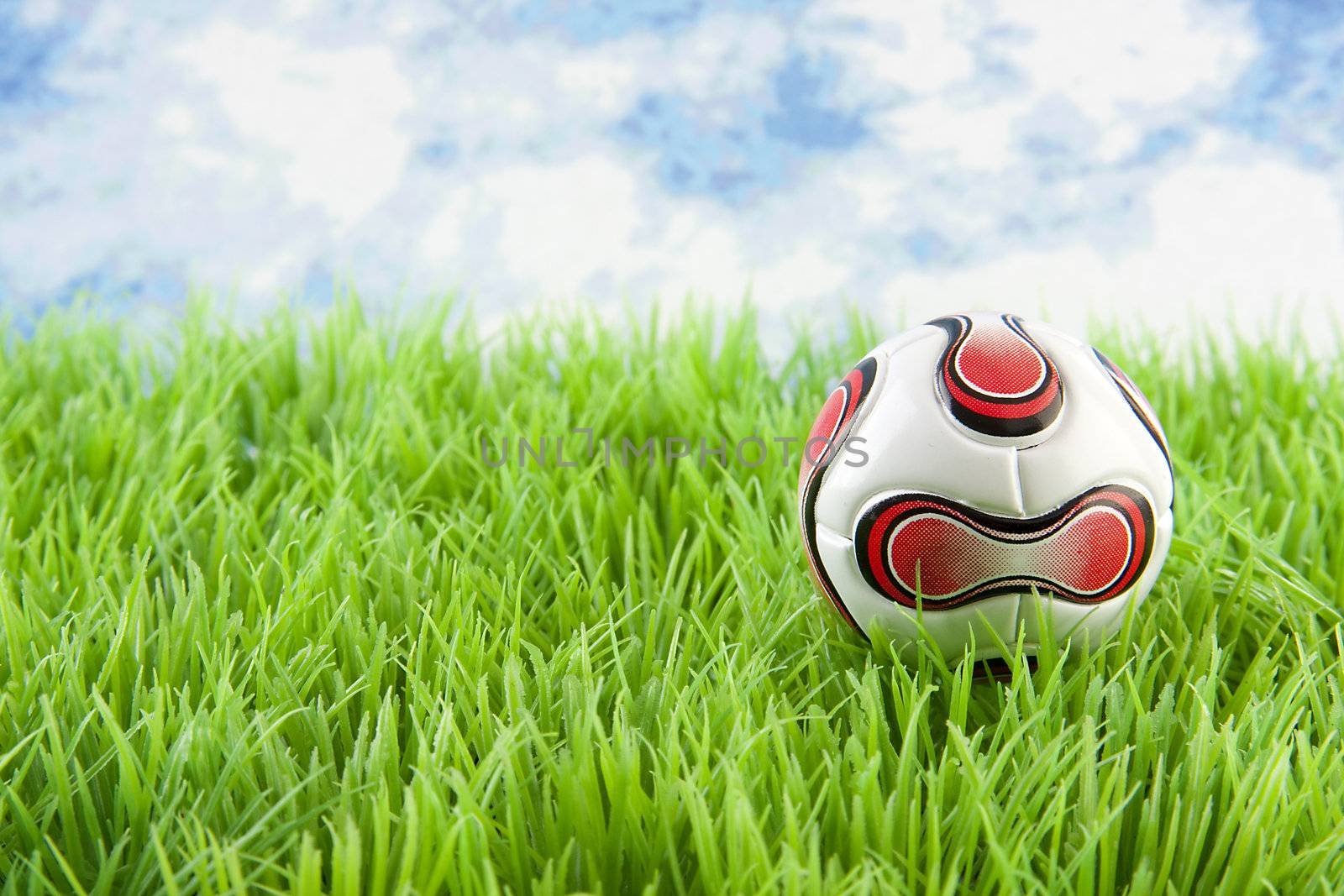 Soccer ball on grass against blue cloudy sky