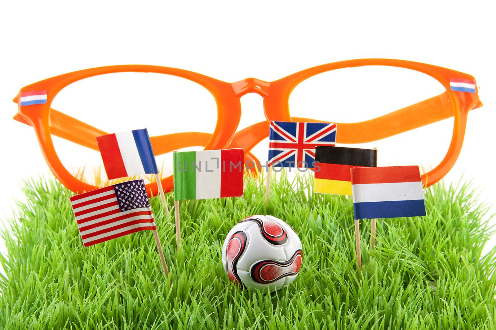 Flags, big orange glasses and ball on soccer field over white background