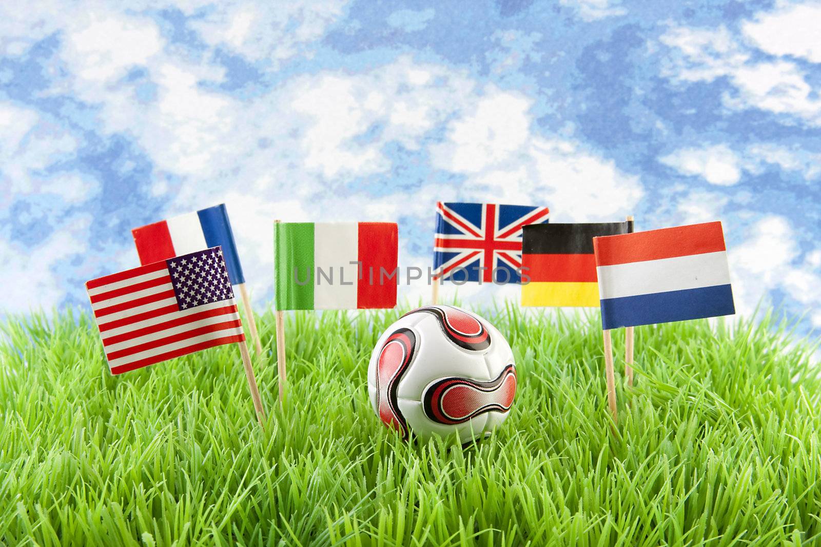 Flags and ball on soccer field over cloudy blue sky