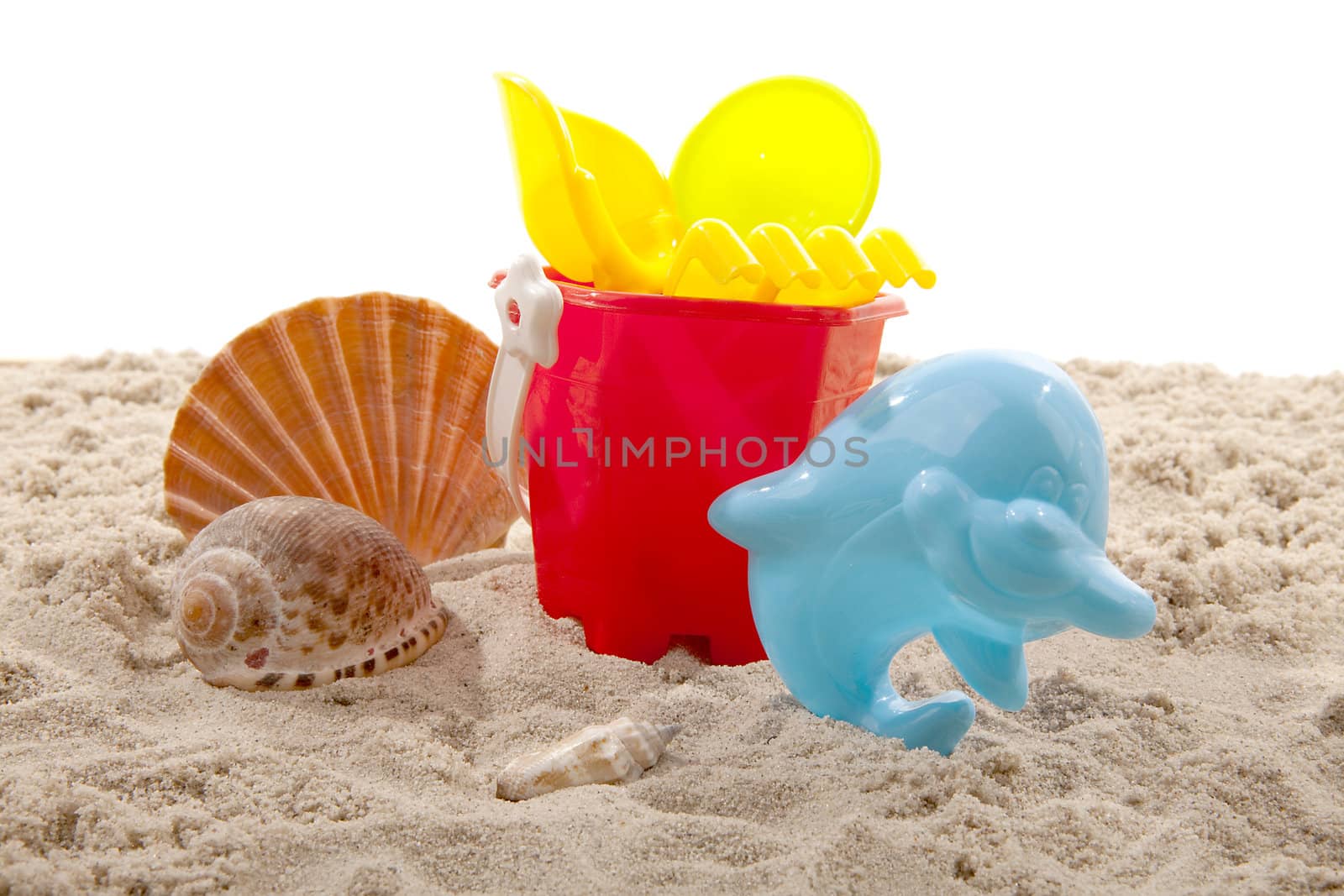 colorful plastic toys for the beach on sand over white background