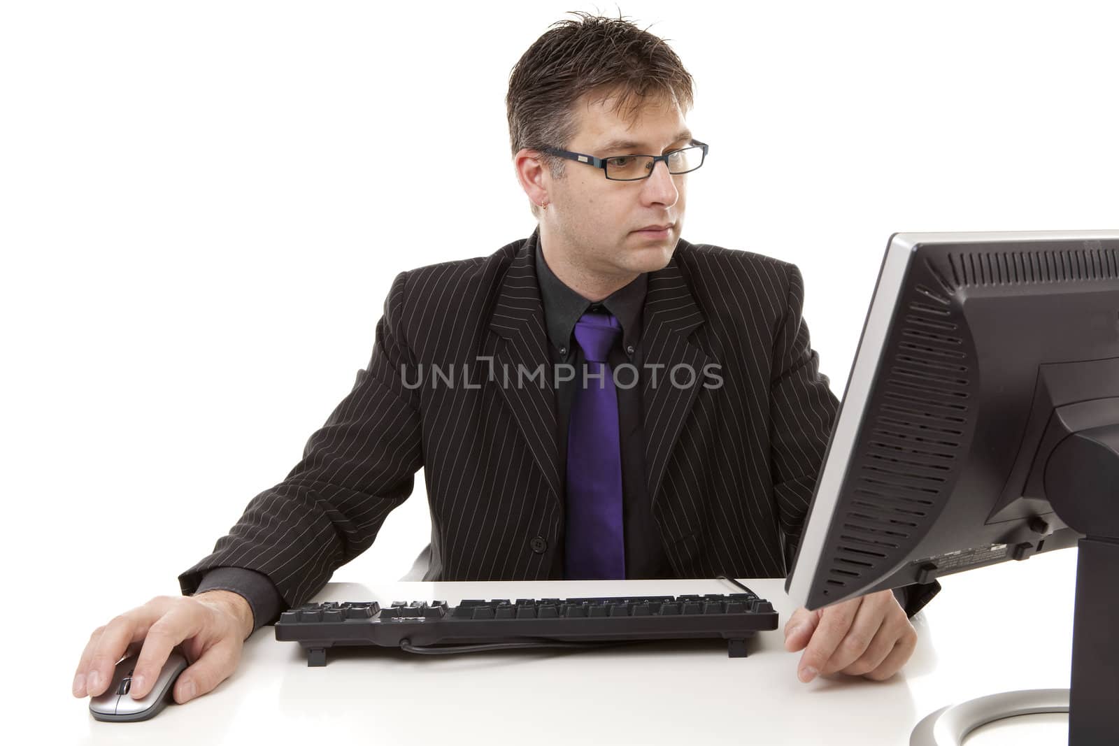 Businessman sitting behind desk at work, looking at monitor, over white background