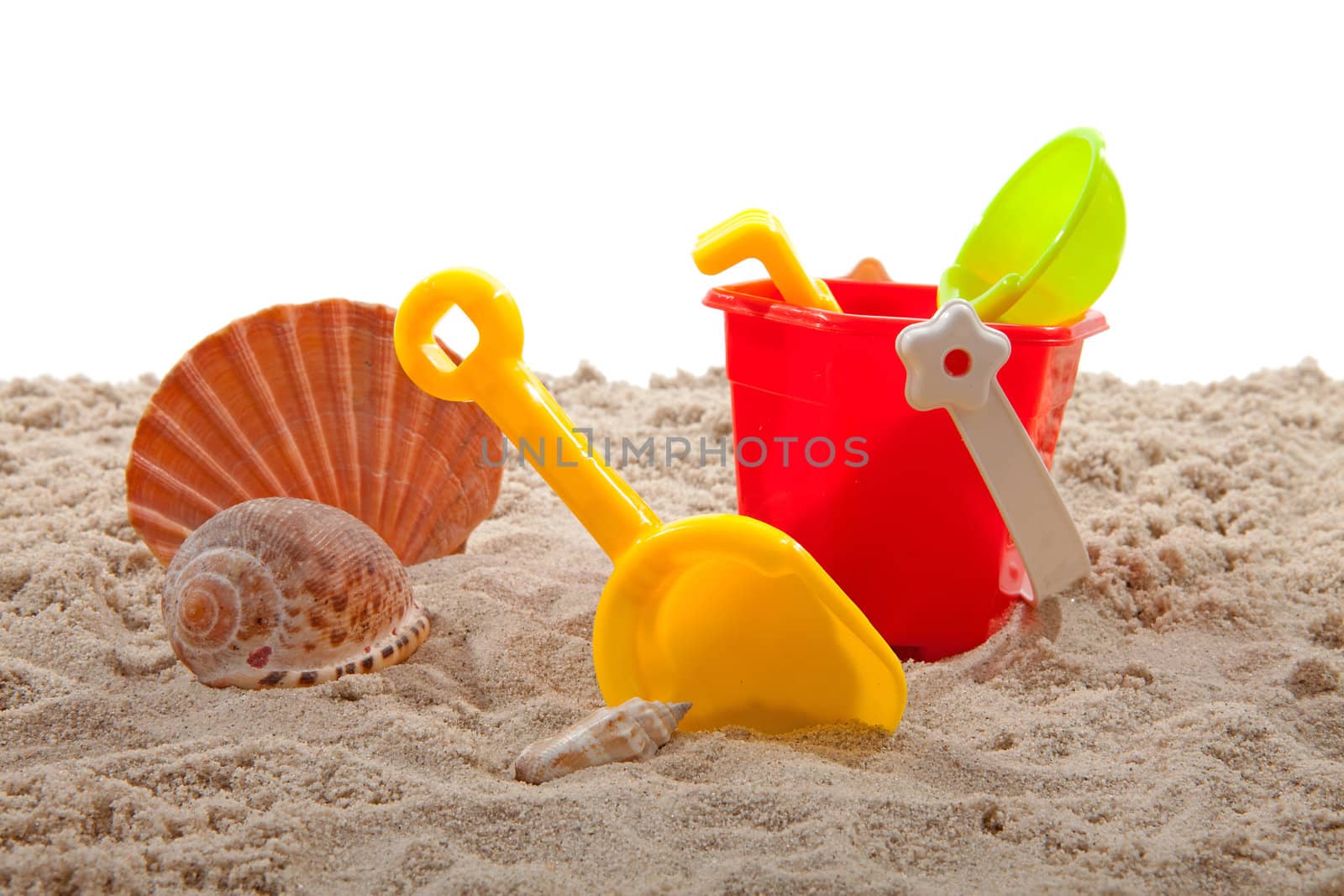 plastic toys for beach and shell on sand over white background