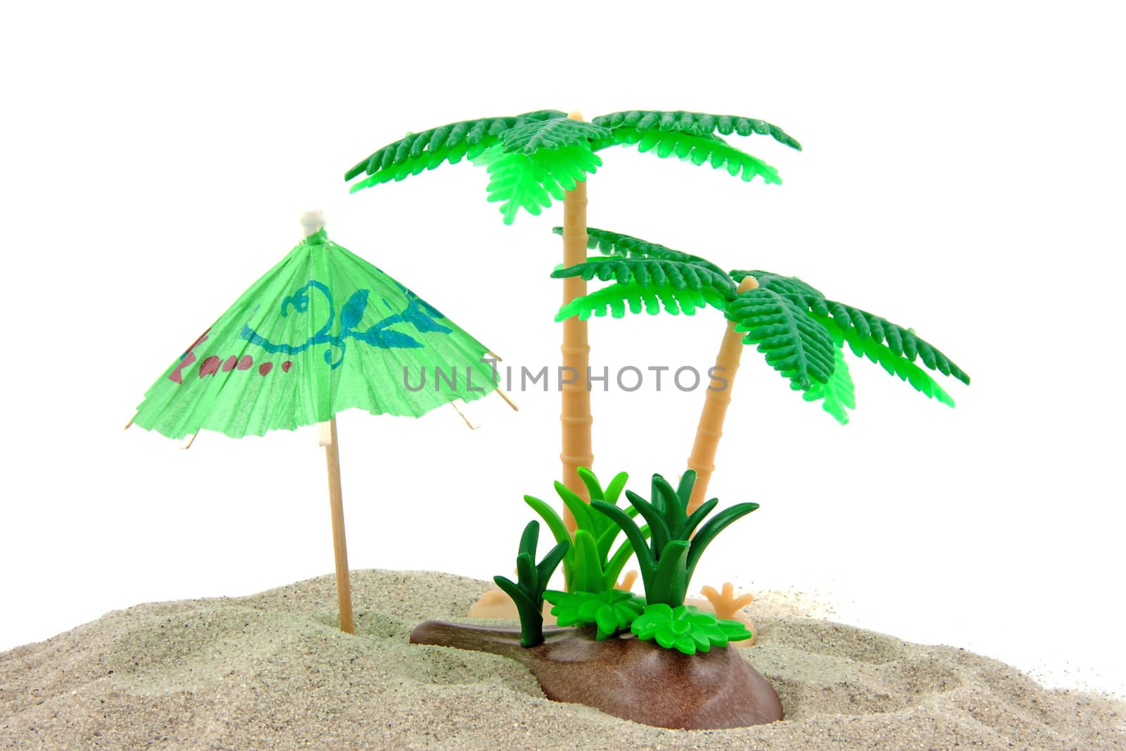 plastic toys and paper umbrella on beach scene over white background
