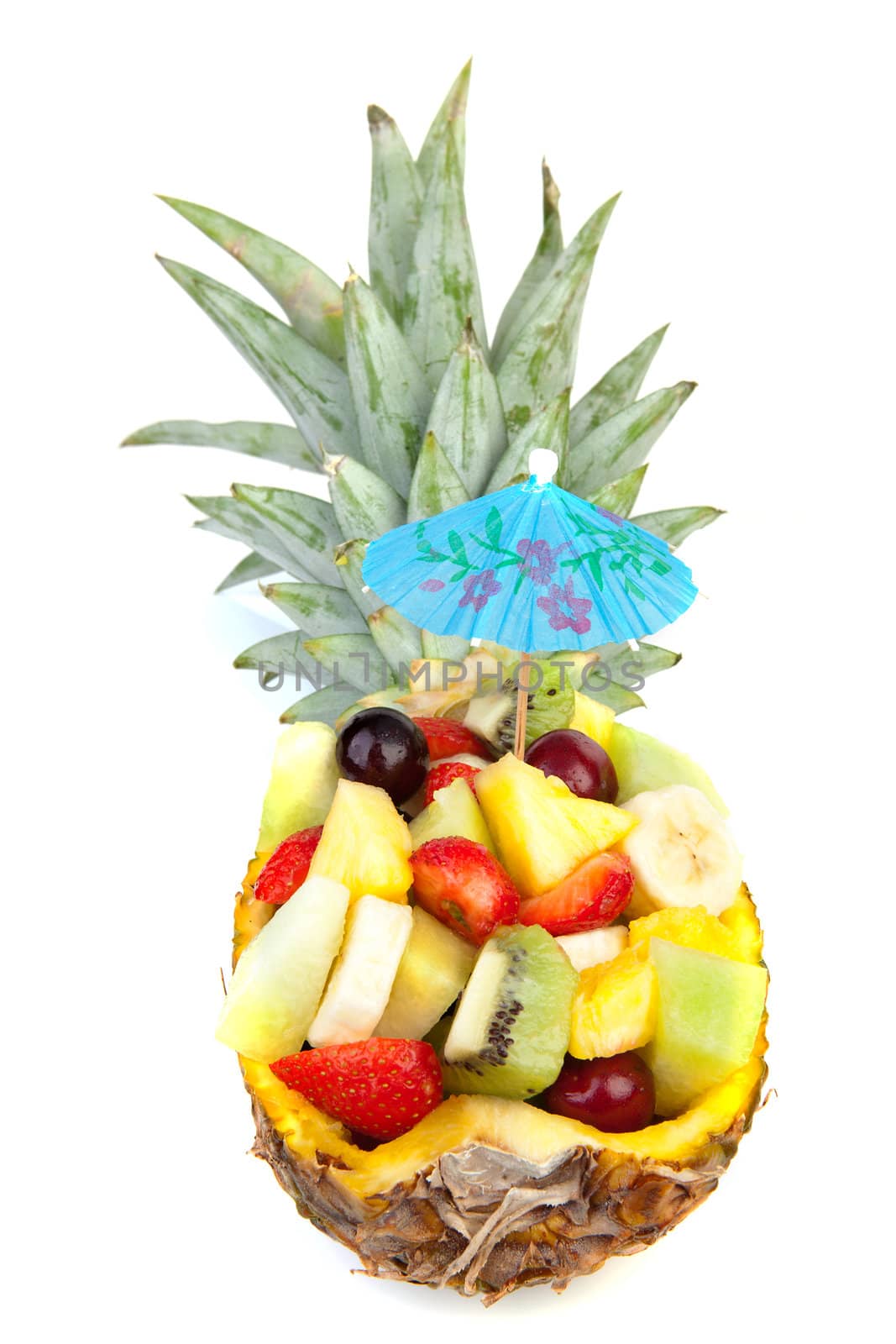Hollowed pineapple filled with fresh summer fruits over white background