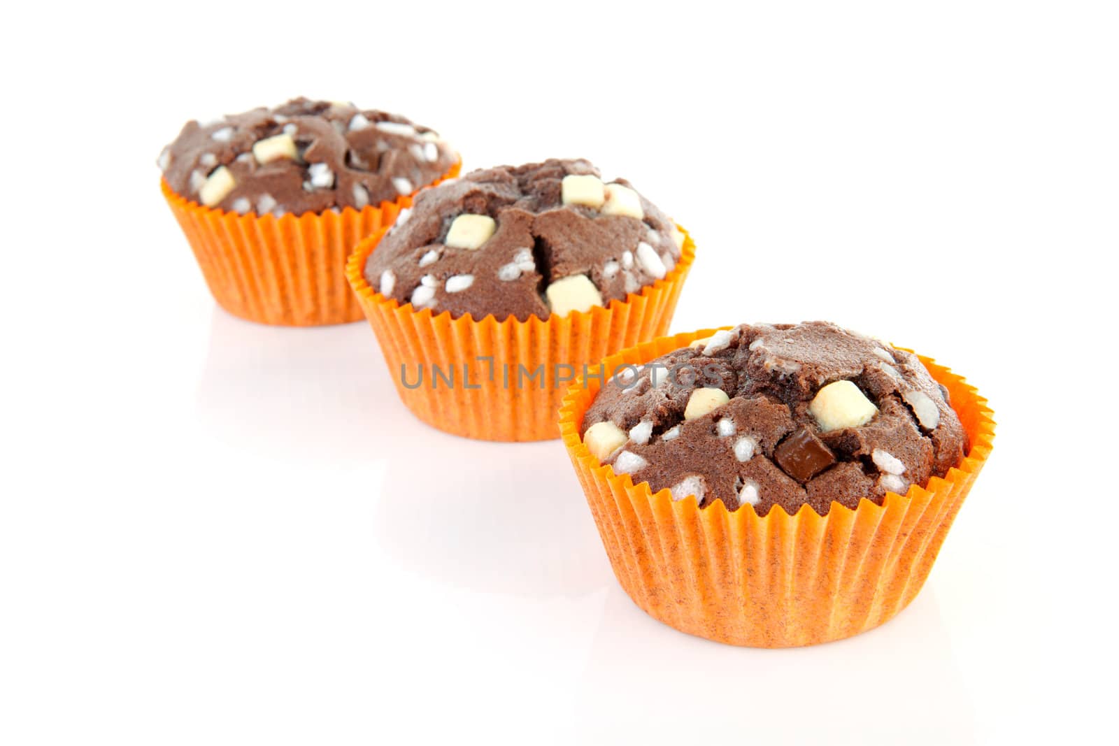 three brown home baked cupcake with chocolate pieces isolated on white background