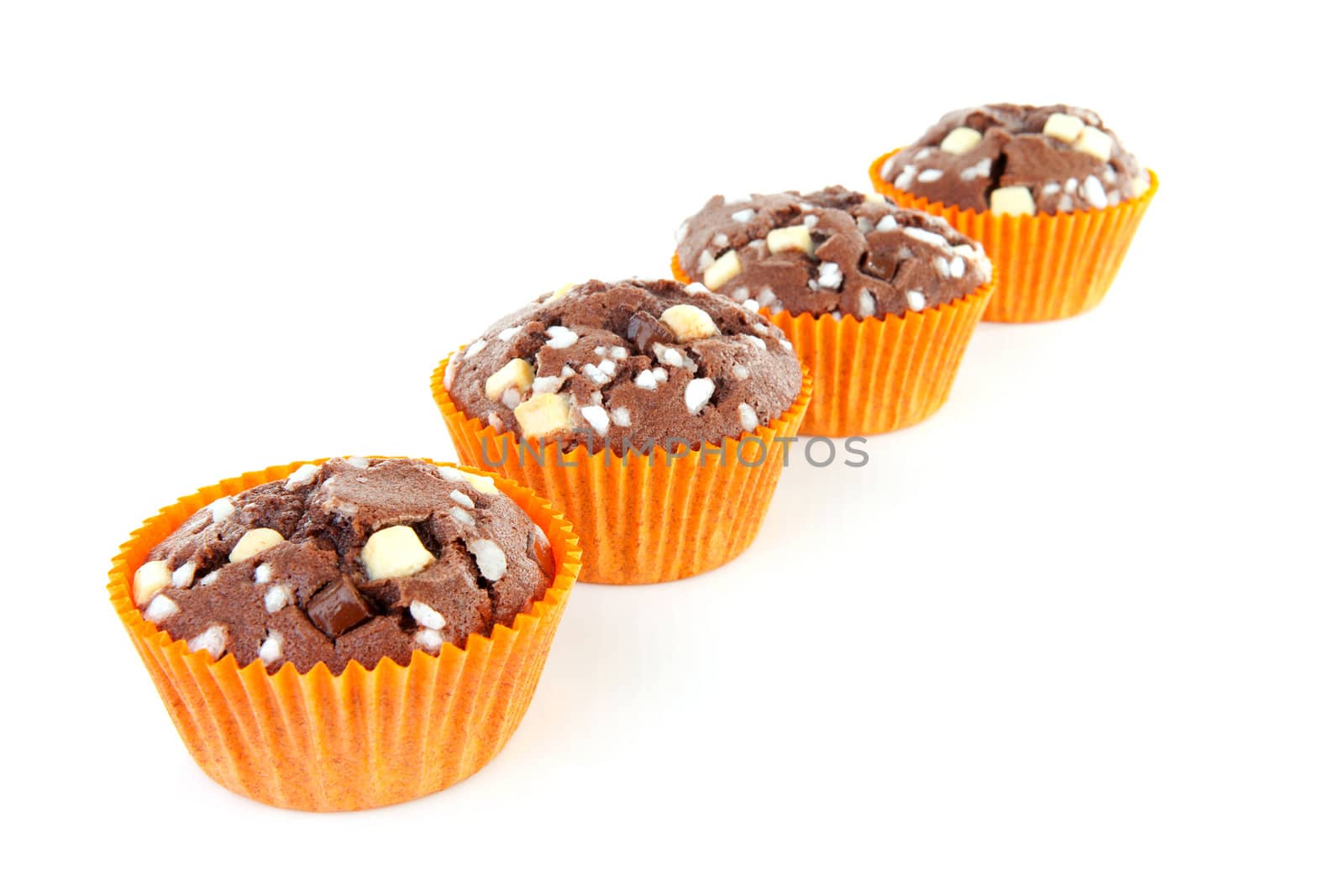 four brown home baked cupcake with chocolate pieces in a row isolated on white background