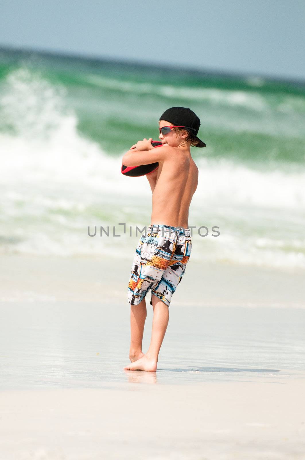 Boy Playing Football At the Beach by tammykayphoto